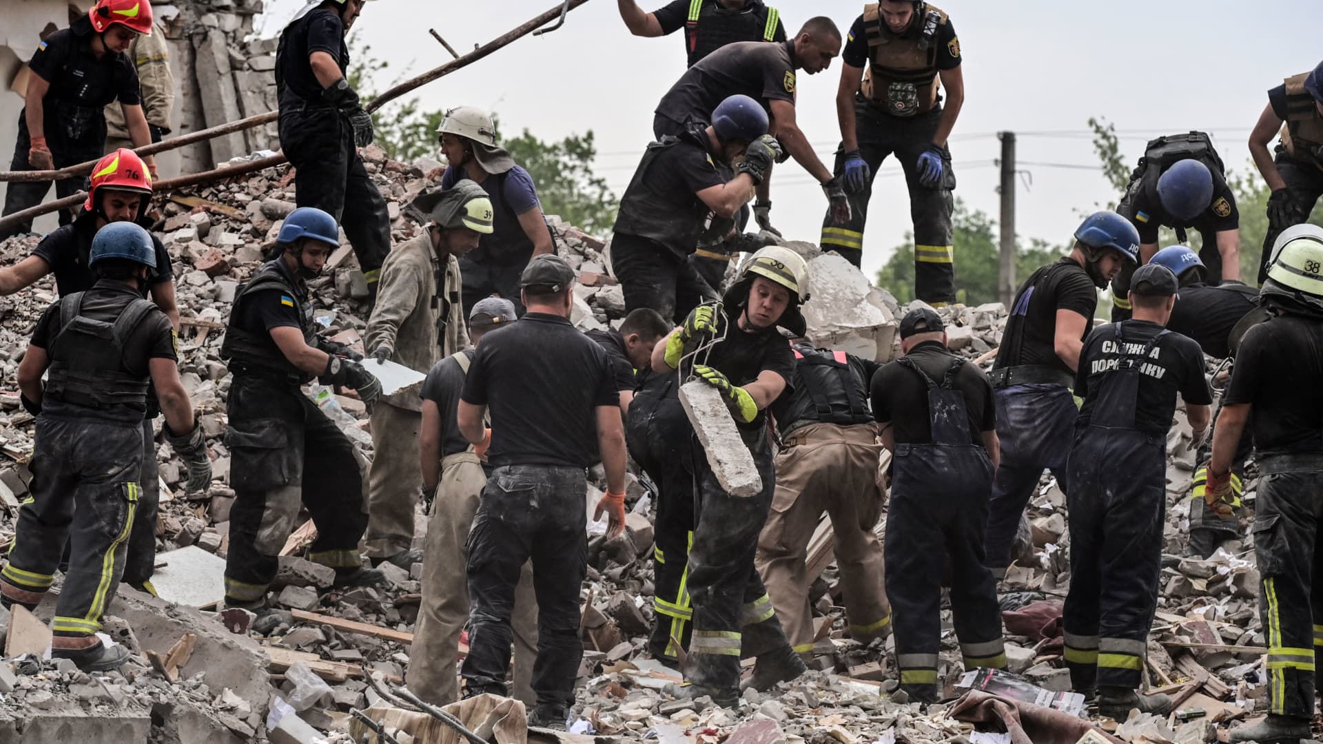 Firefighters and rescue workers clear the scene after a building was partially destroyed by shelling, in Chasiv Yar, eastern Ukraine, on July 10, 2022.