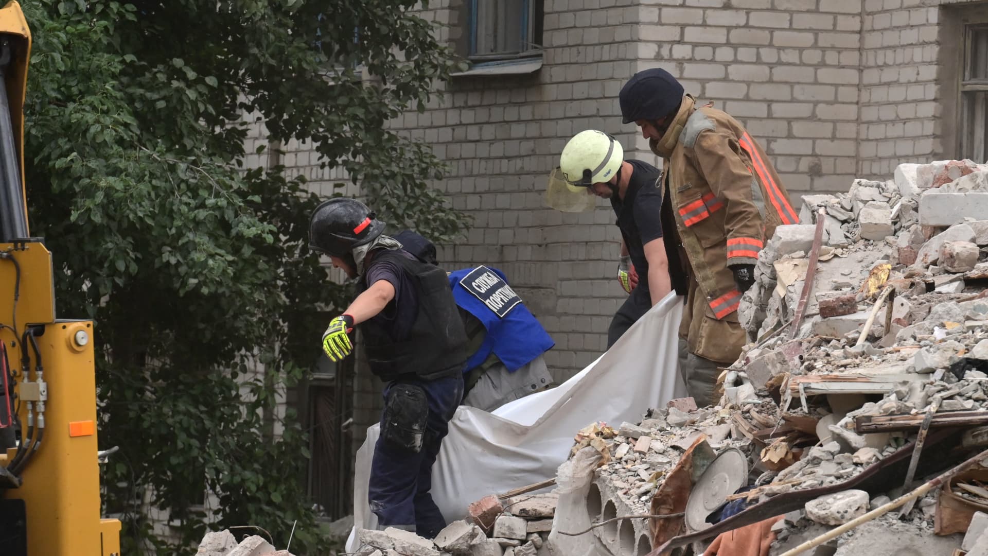 Firefighters and members of a rescue team carry a body after a building was partialy destroyed following shelling, in Chasiv Yar, eastern Ukraine, on July 10, 2022.