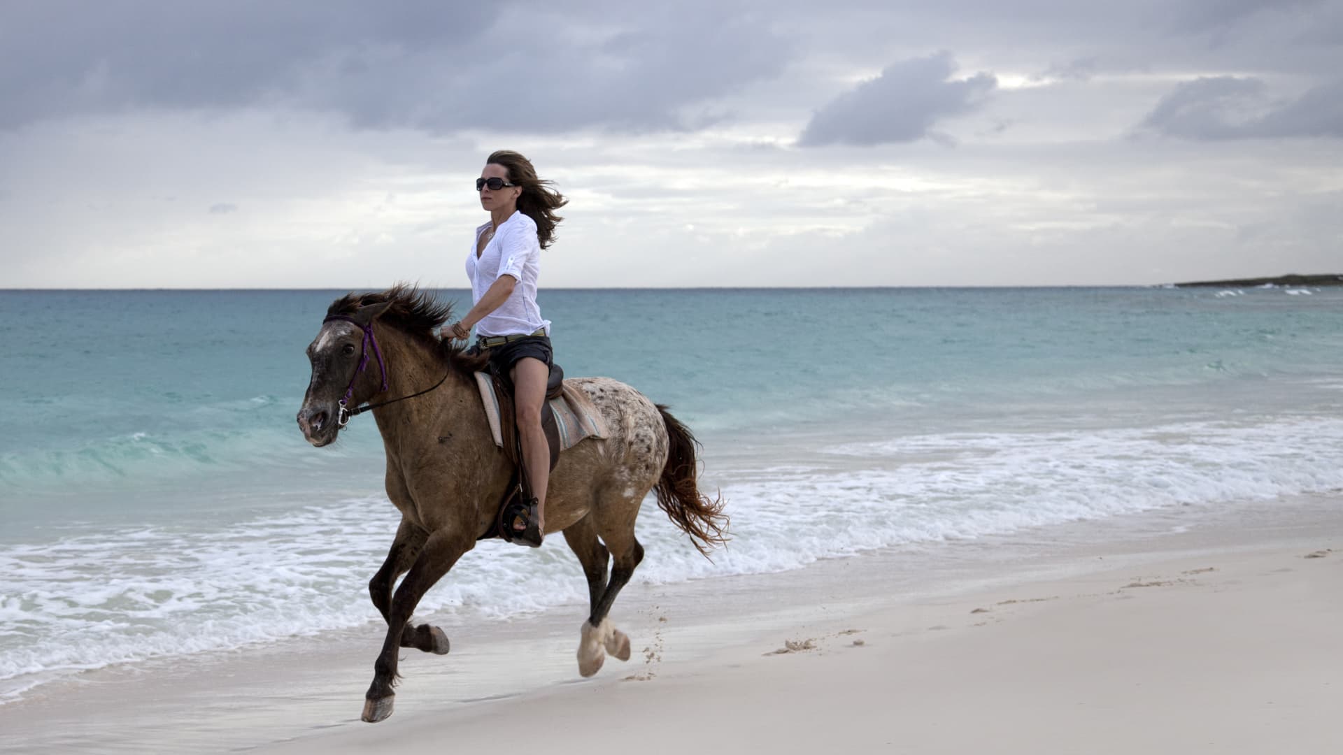 Woman riding a horse on a tropical beach in Anguilla