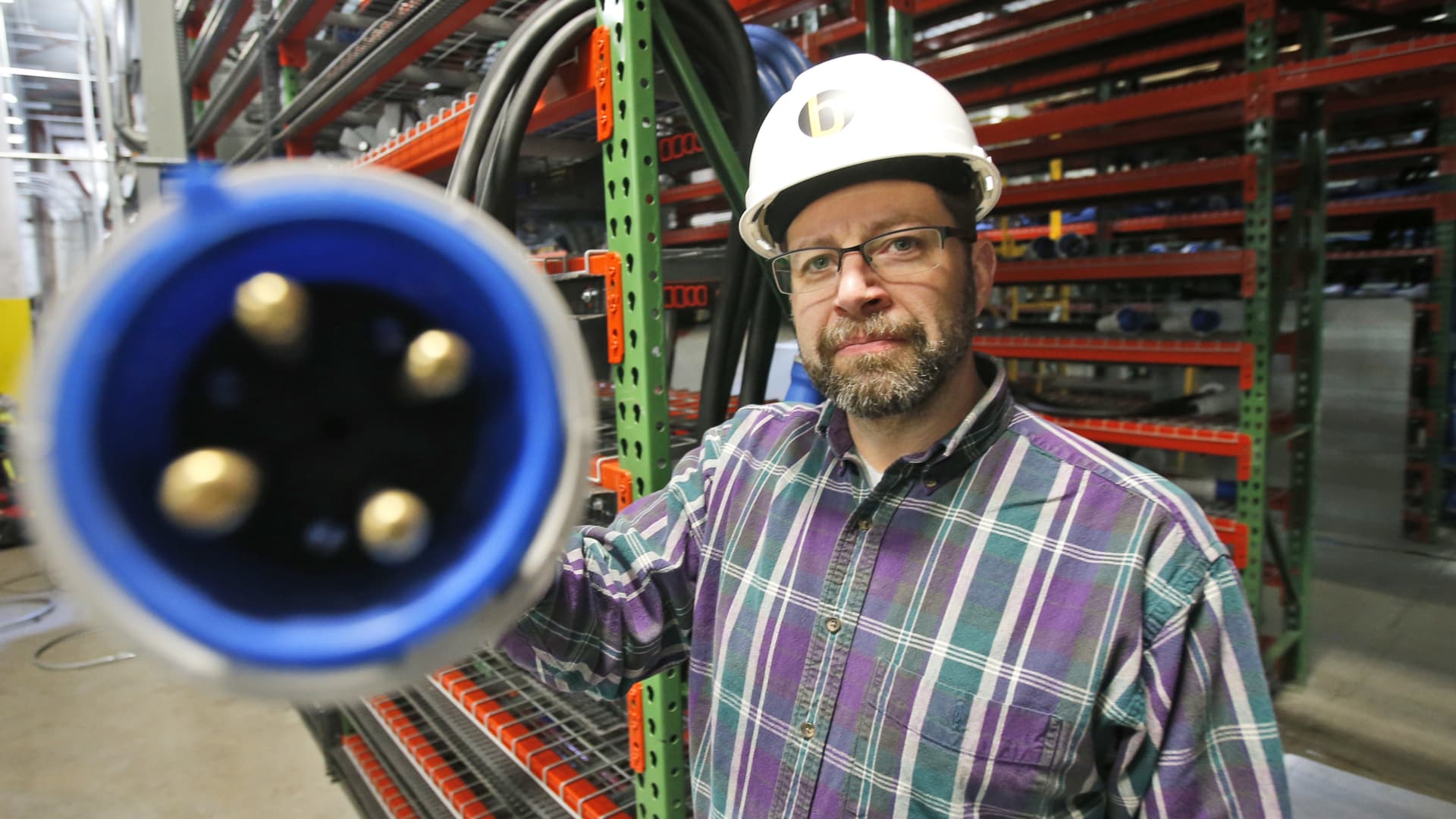 Director of Technology, Shawn Dailey holds a power cable during construction of a Bitcoin data center in Virginia Beach, Va.,