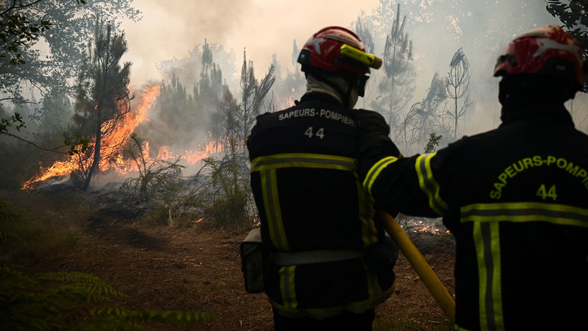 Firefighters take positions as smoke rises from a forest fire near Louchats, as wildfires continue to spread in the Gironde region of southwestern France, July 18, 2022. 