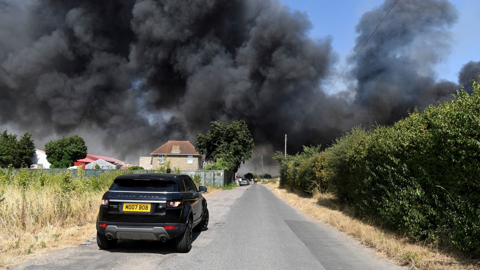 A car drives near a fire that burns during a heatwave, in Rainham, east London, Britain, July 19, 2022. 