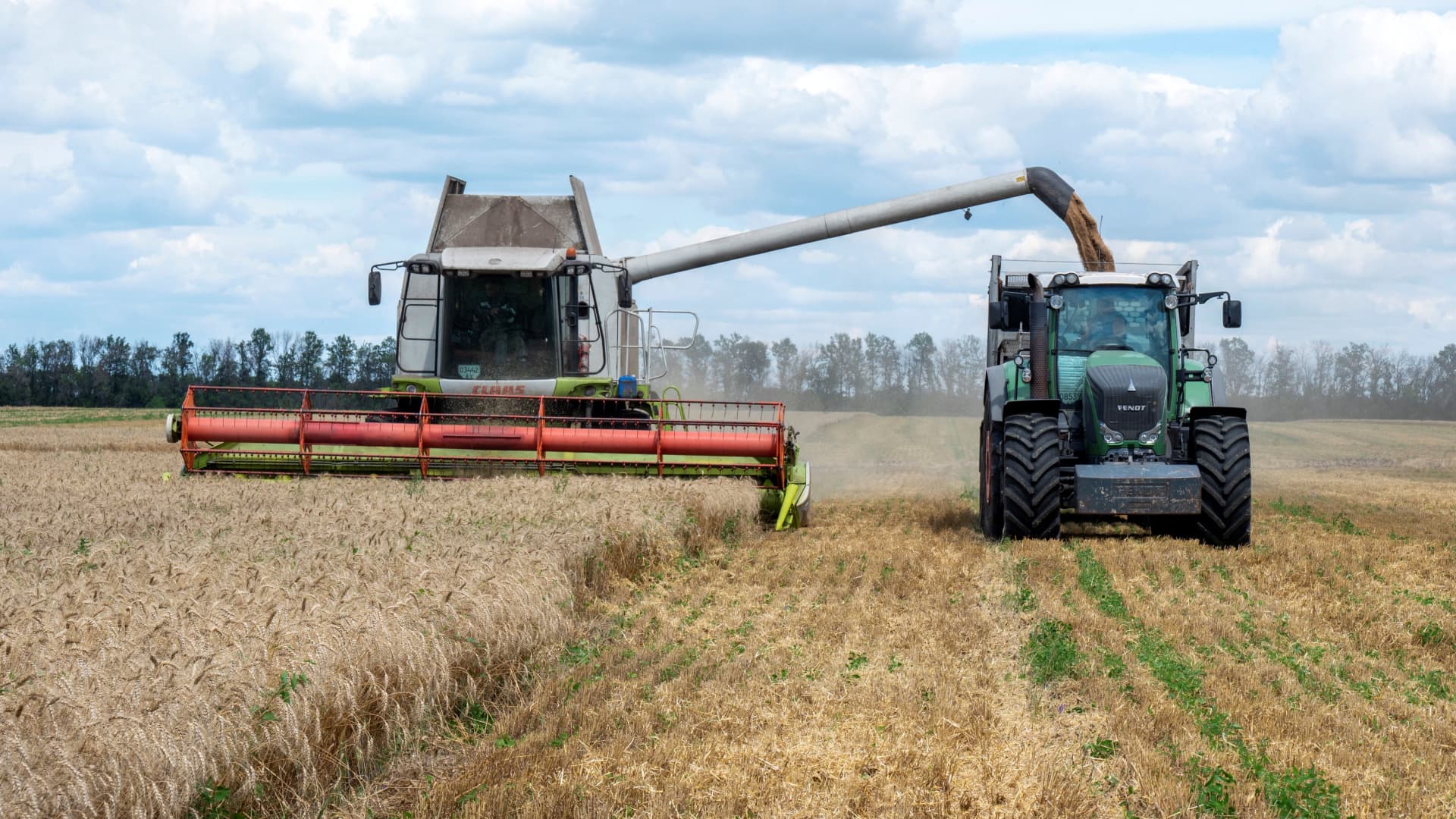 Farmers harvest a wheat field in the Ukrainian Kharkiv region on July 19, 2022, amid Russian invasion of Ukraine. 