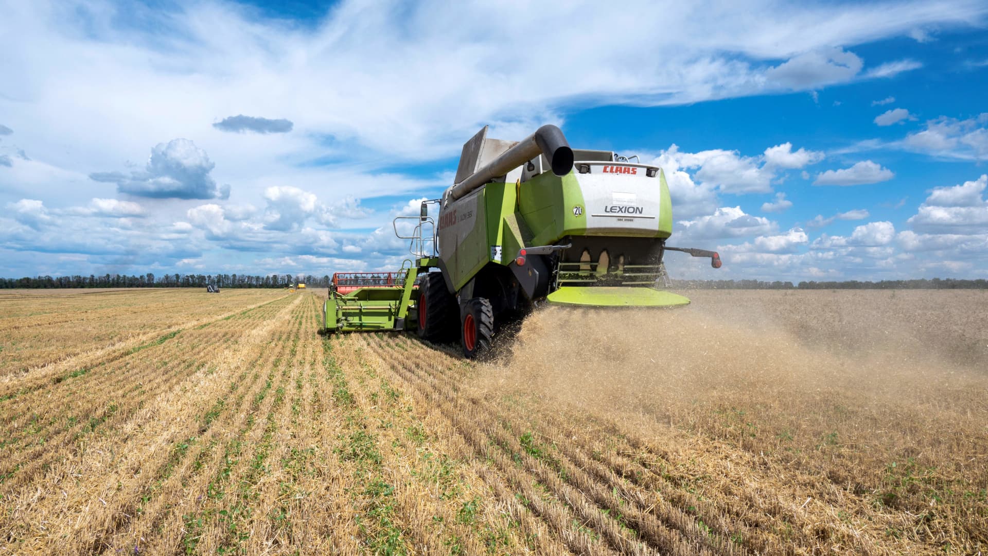 Farmers harvest a wheat field in the Ukrainian Kharkiv region on July 19, 2022, amid Russian invasion of Ukraine. 