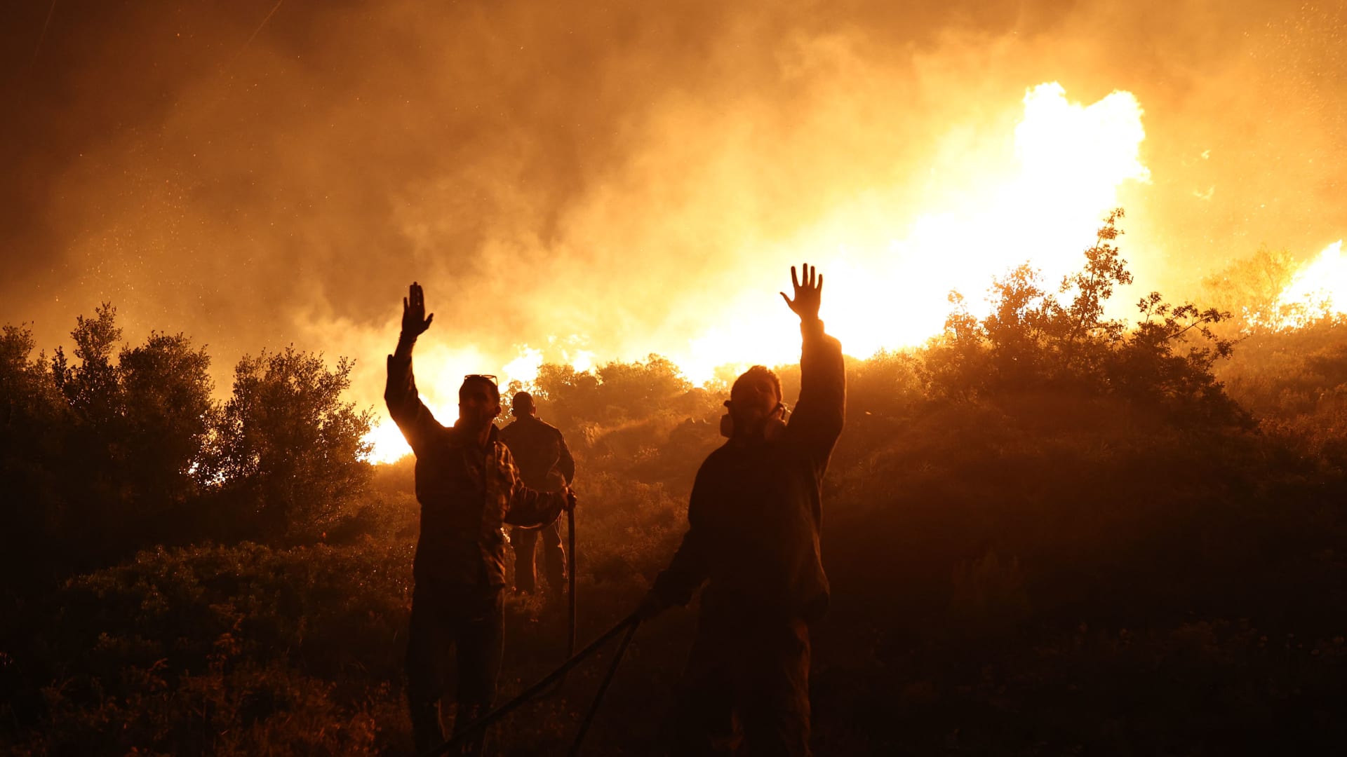 Firefighters gestures as they work to extinguish a wild fire in Drafi agglomeration, north of Athens, on July 19, 2022.