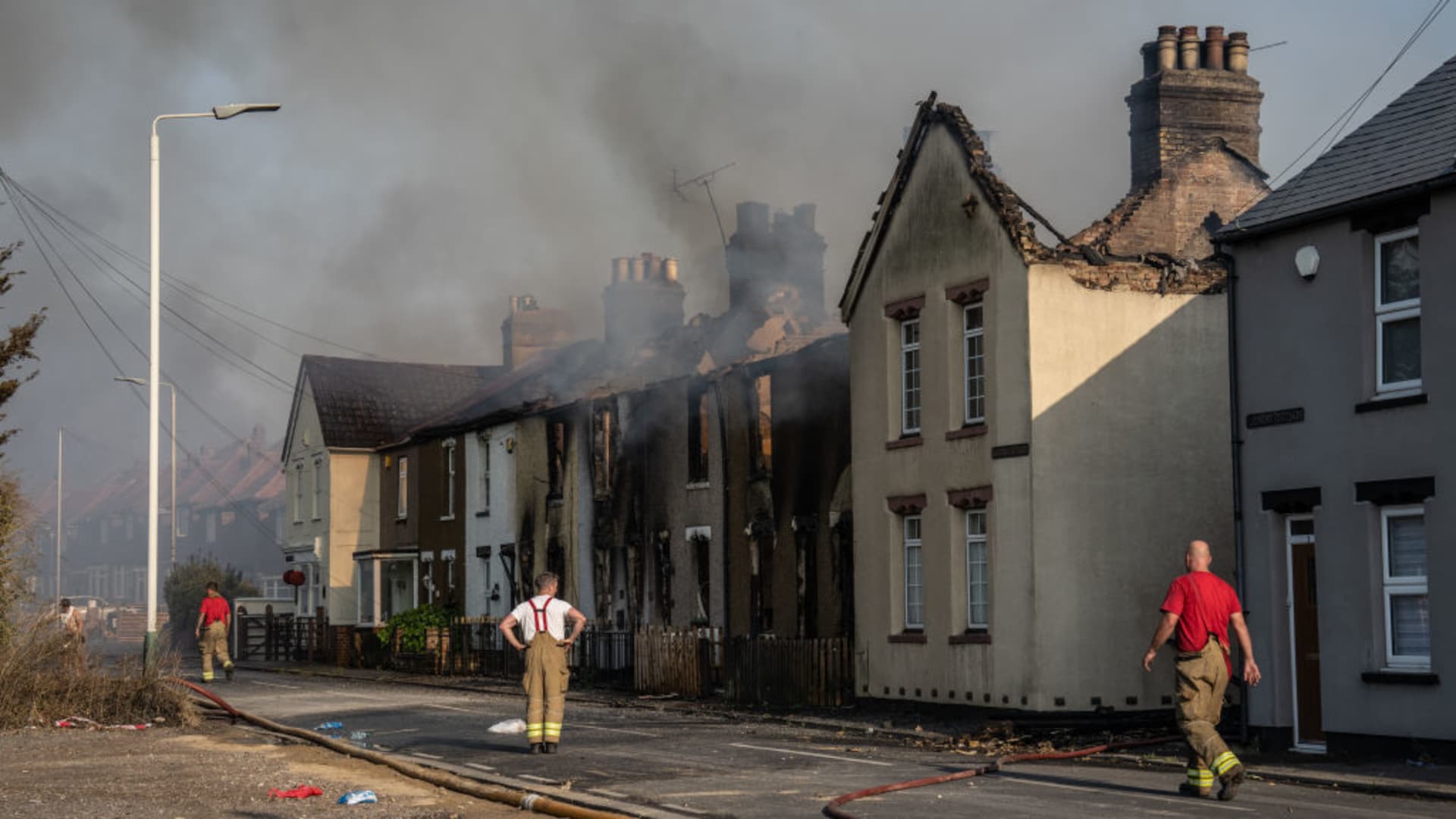 Fireman work next to buildings destroyed by fire on July 19, 2022 in Wennington, England. A series of grass fires broke out around the British capital amid an intense heatwave.