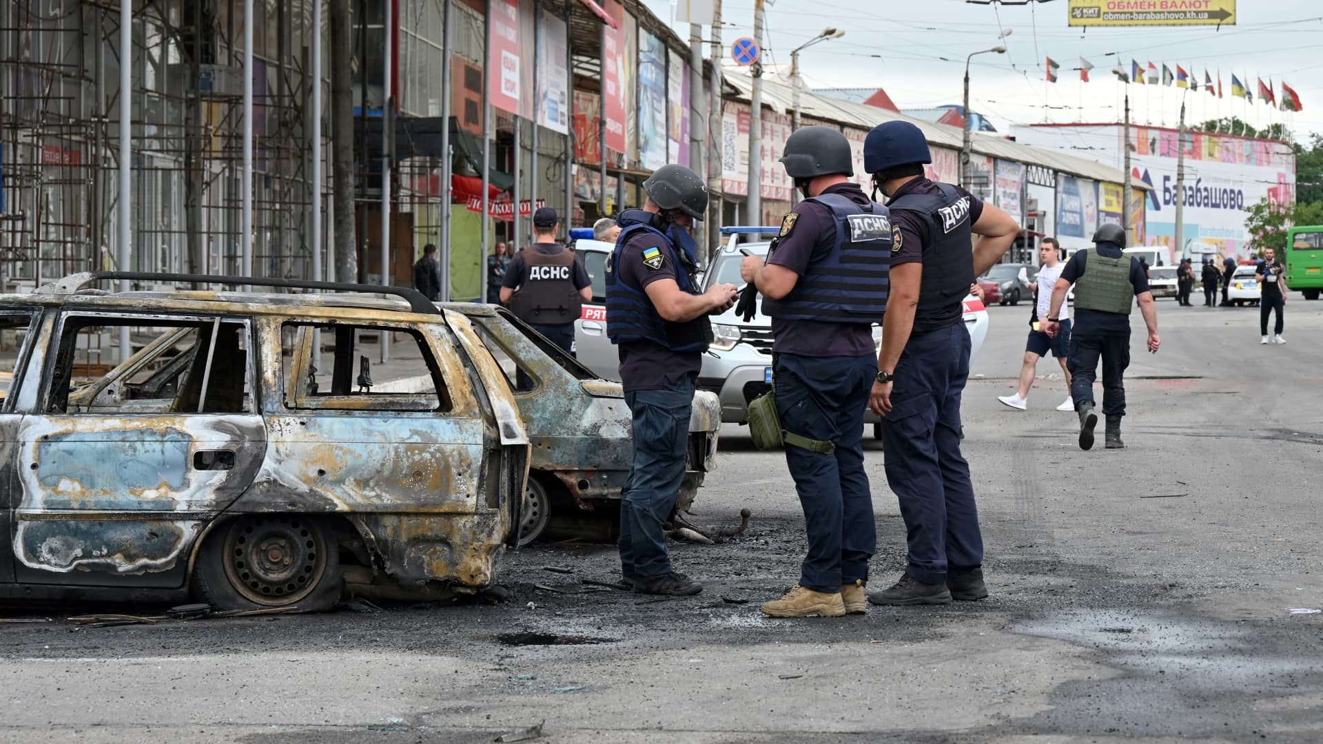 Rescuers stand next to burnt cars after a Russian rocket strike in one of the districts of the second largest Ukrainian city of Kharkiv on July 21, 2022 amid the Russian invasion of Ukraine.