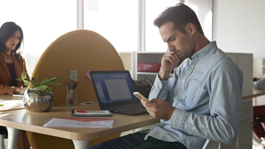 Businessman sitting at office desk, just received bad news on his phone