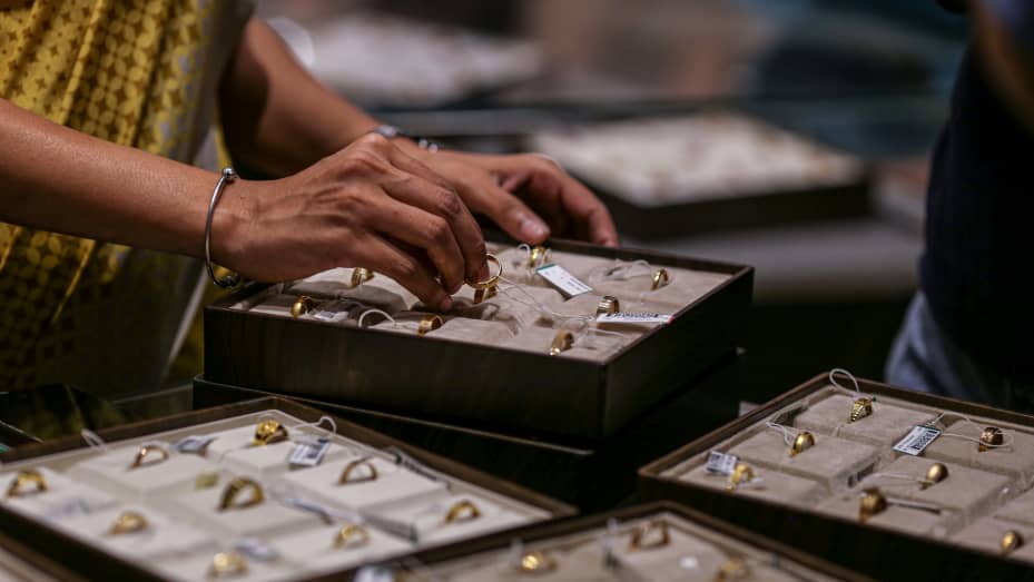 An employee arranging gold rings inside a Titan Co. Tanishq jewelry store during the festival of Dhanteras in Mumbai, India. Gold inched up on Wednesday, as the dollar weakened slightly, while investors waited for a key decision on interest rates from the U.S. Federal Reserve which could influence the outlook for bullion, amid growing worries over the state of the economy.