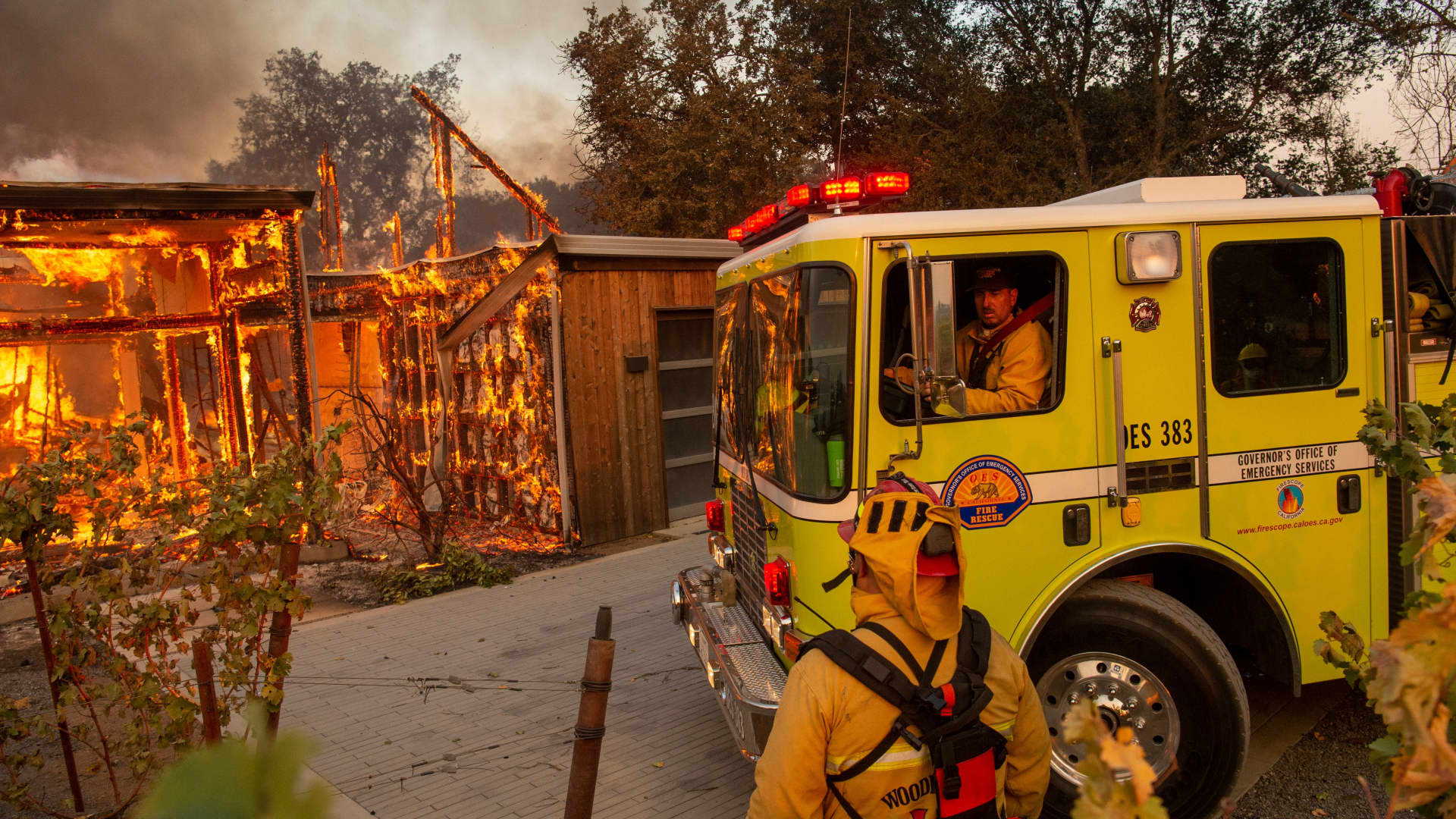 Firefighters pull up to a burning house during the Kincade fire in Healdsburg, California, on Oct. 27, 2019.