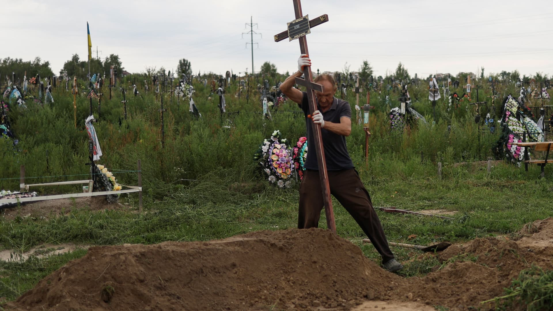 Volunteers lower into a grave a coffin with one of fourteen unidentified persons killed by Russian troops, amid Russia's attack on Ukraine continues, during a burial ceremony in the town of Bucha, in Kyiv region, Ukraine August 9, 2022.