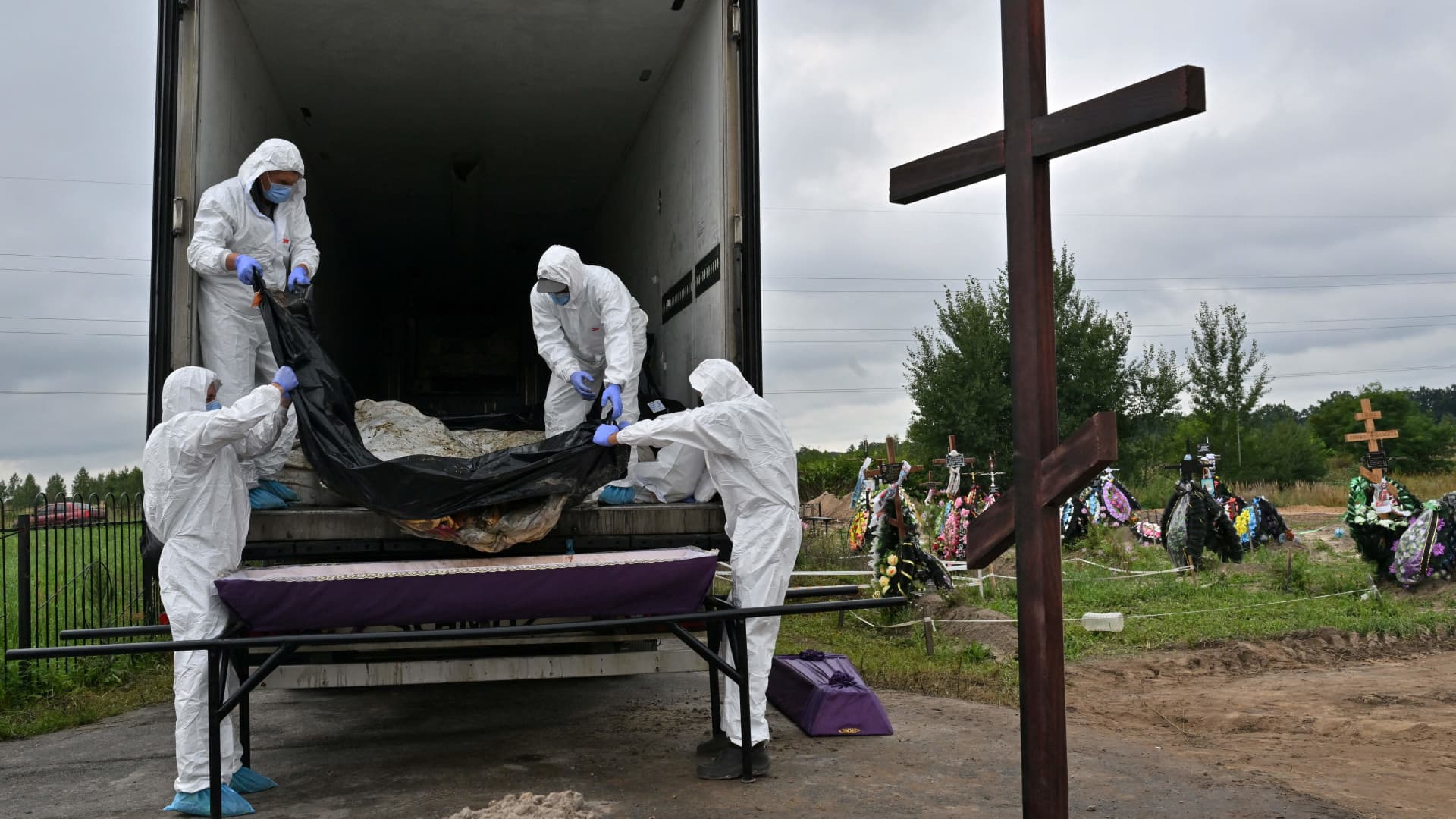 Municipal workers remove body bags of some twelve unidentified civilians from the back of a morgue container to be laid in coffins ready for burial at a local cemetary in the city of Bucha, Kyiv region, on August 11, 2022. 