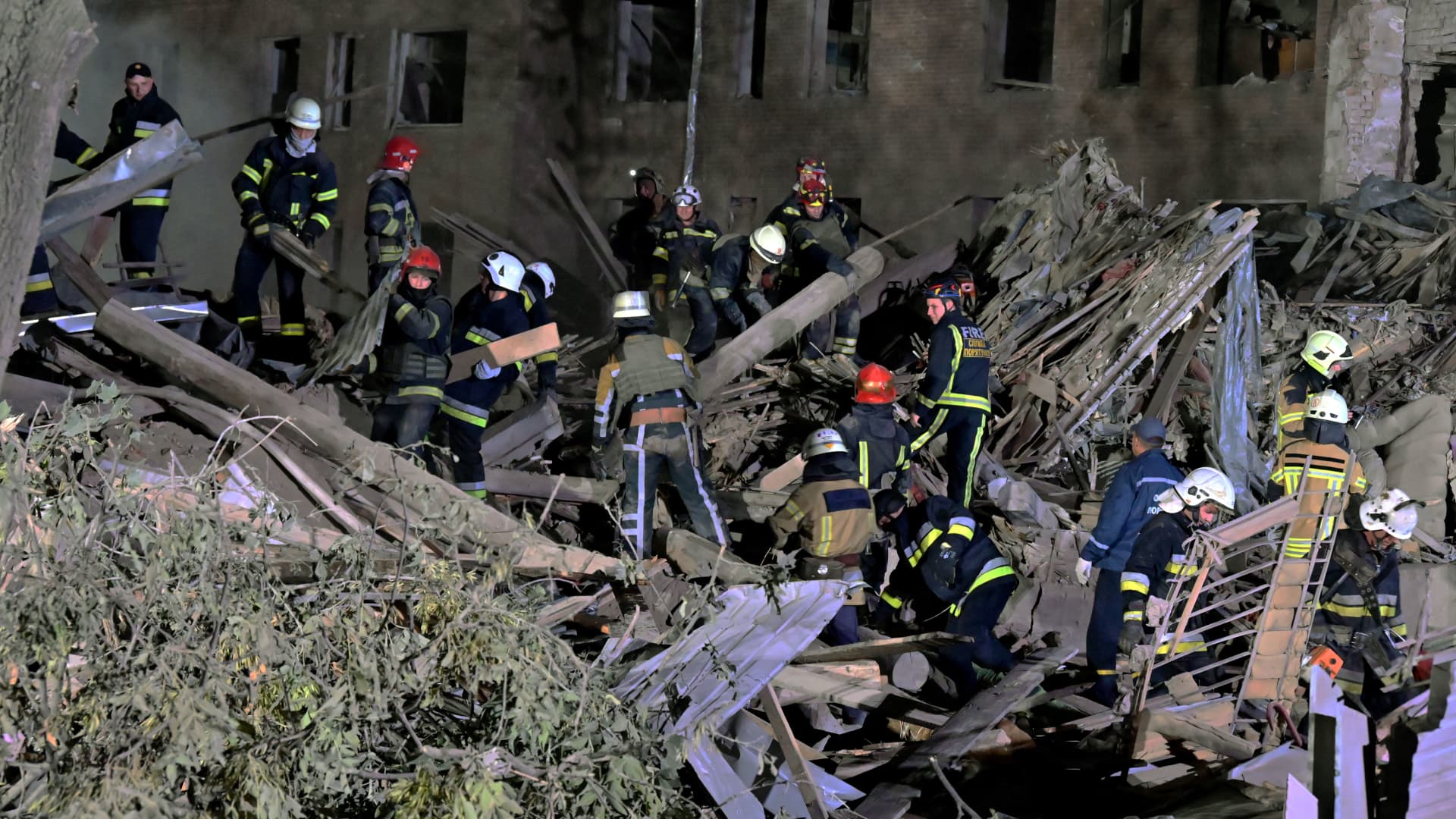 Rescue workers inspect the site of a destroyed hostel as a result of a missile strike in the second-largest Ukrainian city of Kharkiv on Aug. 17, 2022.