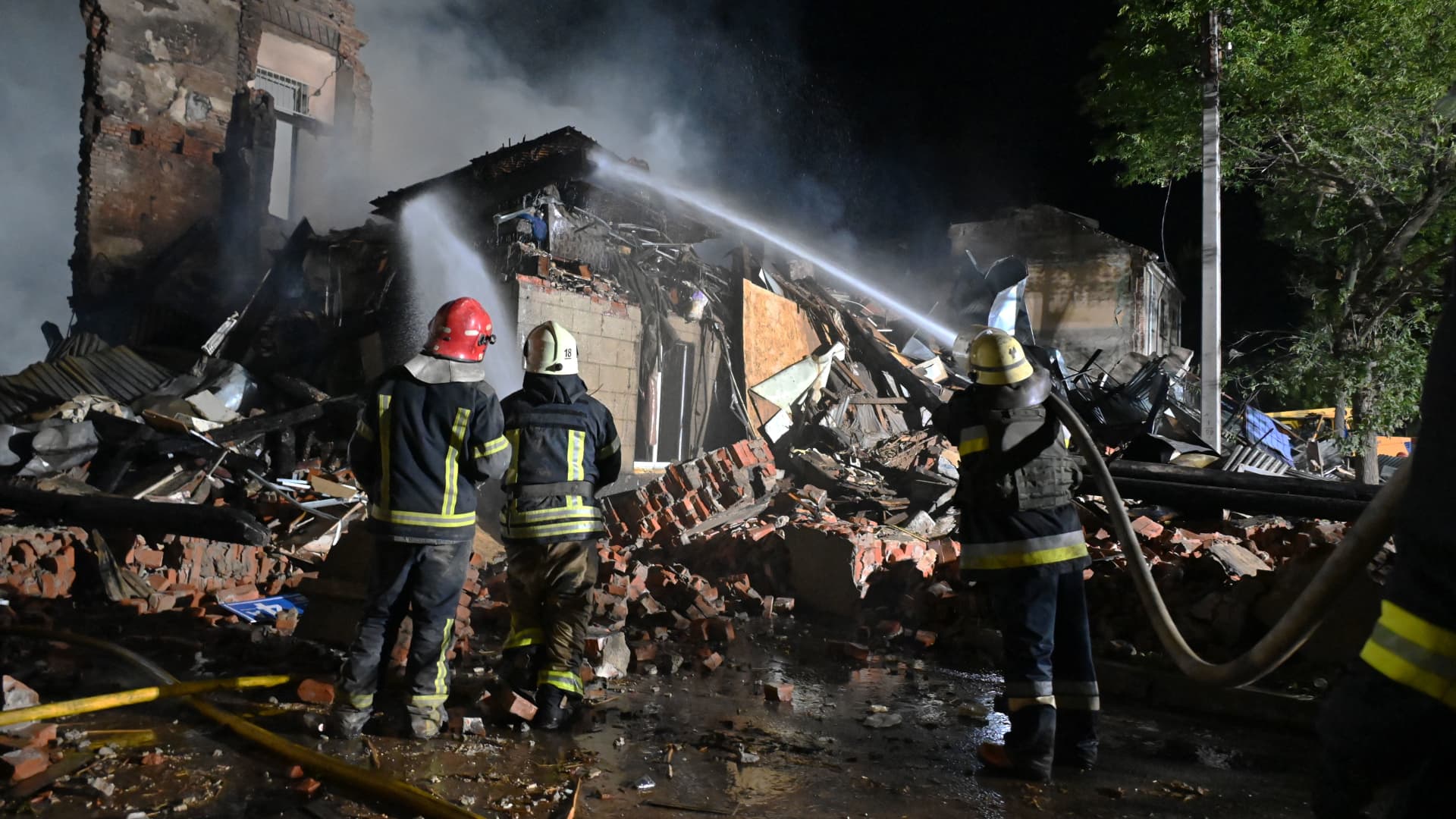 Firefighters extinguish a fire at the site of a destroyed hostel as a result of a missile strike in the second largest Ukrainian city of Kharkiv late on August 17, 2022, amid Russia's military invasion of Ukraine. 
