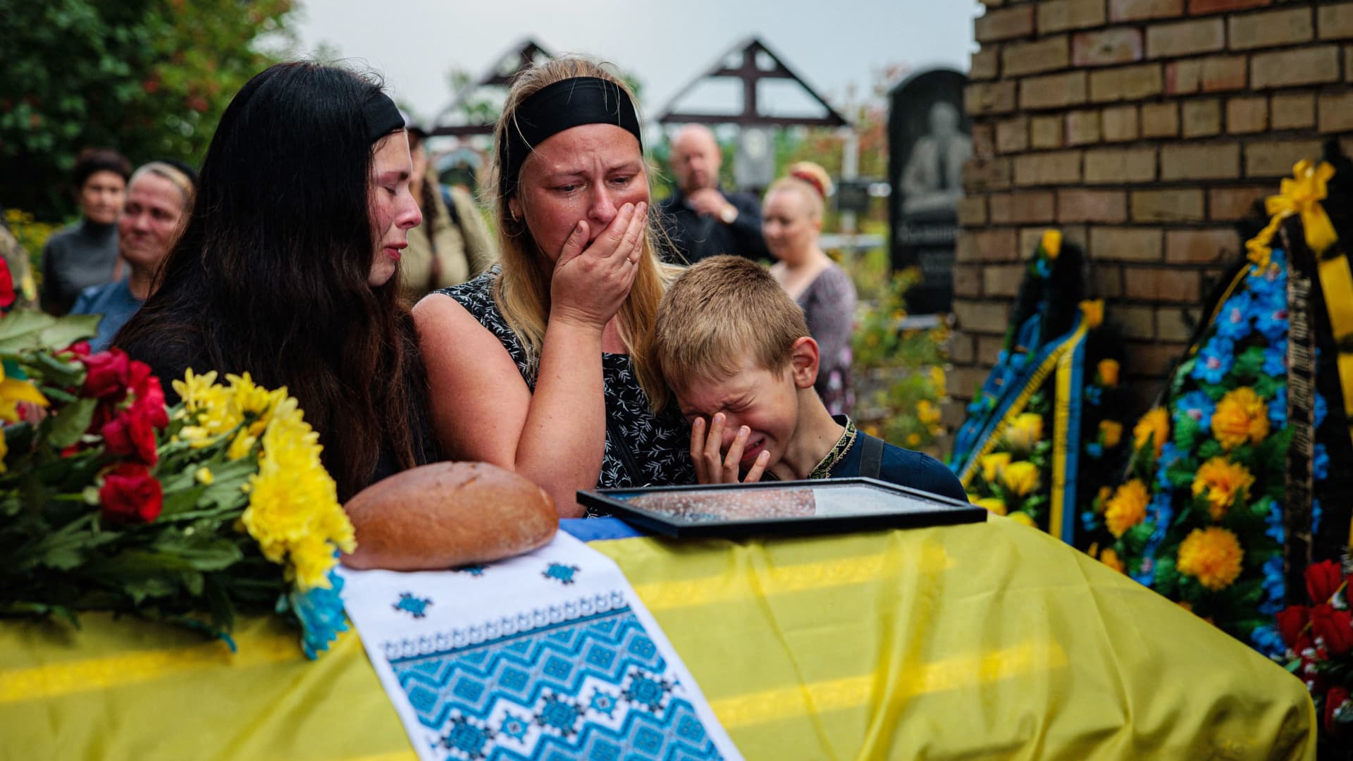 TOPSHOT - Family members mourn next to the coffin of Ukrainian serviceman Anton Savytskyi during a funeral ceremony at Bucha's cemetery in Kyiv region on August 13, 2022, amid the Russian military invasion of Ukraine.