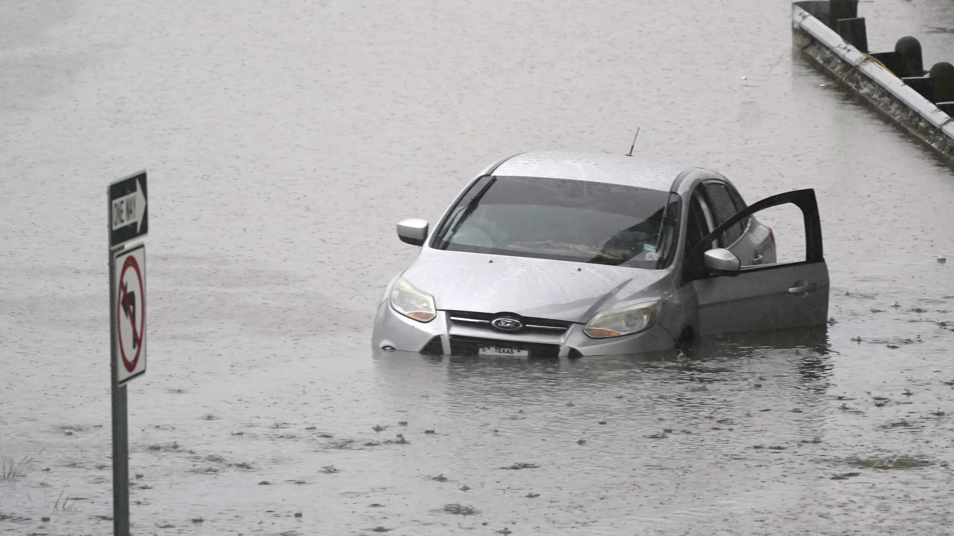 A car sits in flood waters covering a closed highway in Dallas, Monday, Aug. 22, 2022.