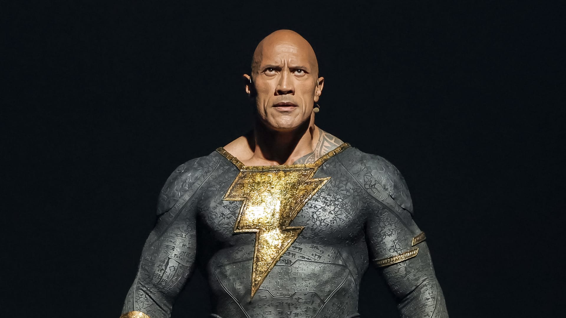 Dwayne Johnson dressed as Black Adam speaks onstage at the Warner Bros. theatrical session with 