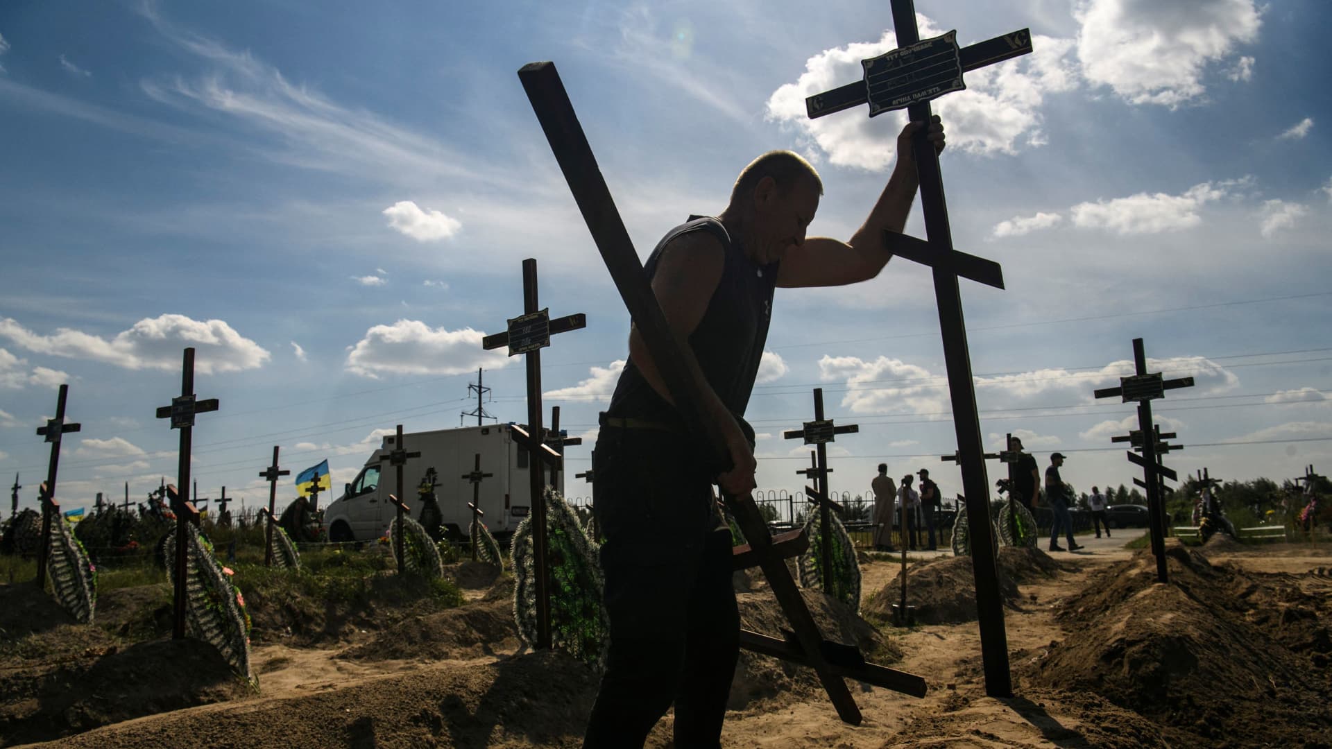 A volunteer places a cross onto a grave of one of fifteen unidentified people killed by Russian troops, amid Russia's attack on Ukraine continues, during a burial ceremony in the town of Bucha, in Kyiv region, Ukraine September 2, 2022.