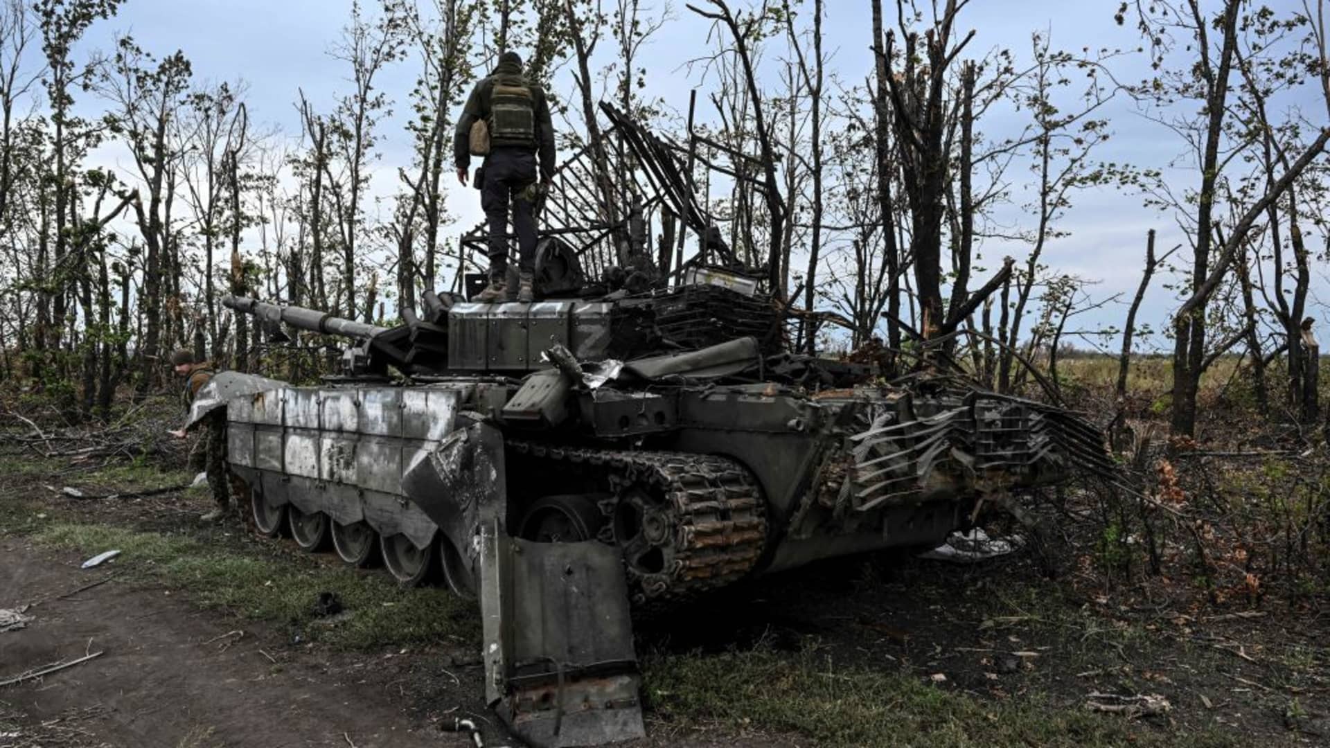 This photograph taken on September 11, 2022, shows a Ukrainian soldier standing atop an abandoned Russian tank near a village on the outskirts of Izyum, Kharkiv Region, eastern Ukraine, amid the Russian invasion of Ukraine.