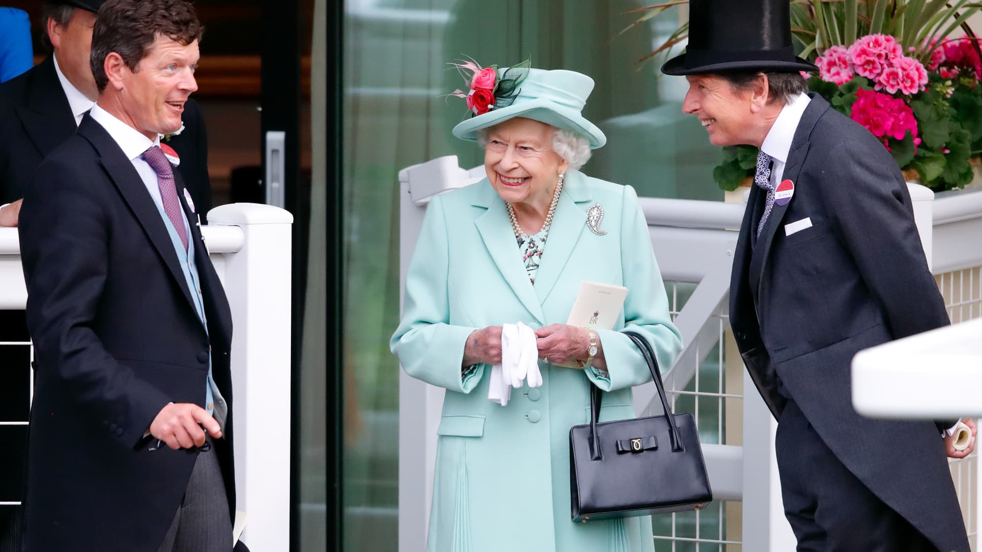 Queen Elizabeth II in her classic matching outfit, with a Launer London bag.