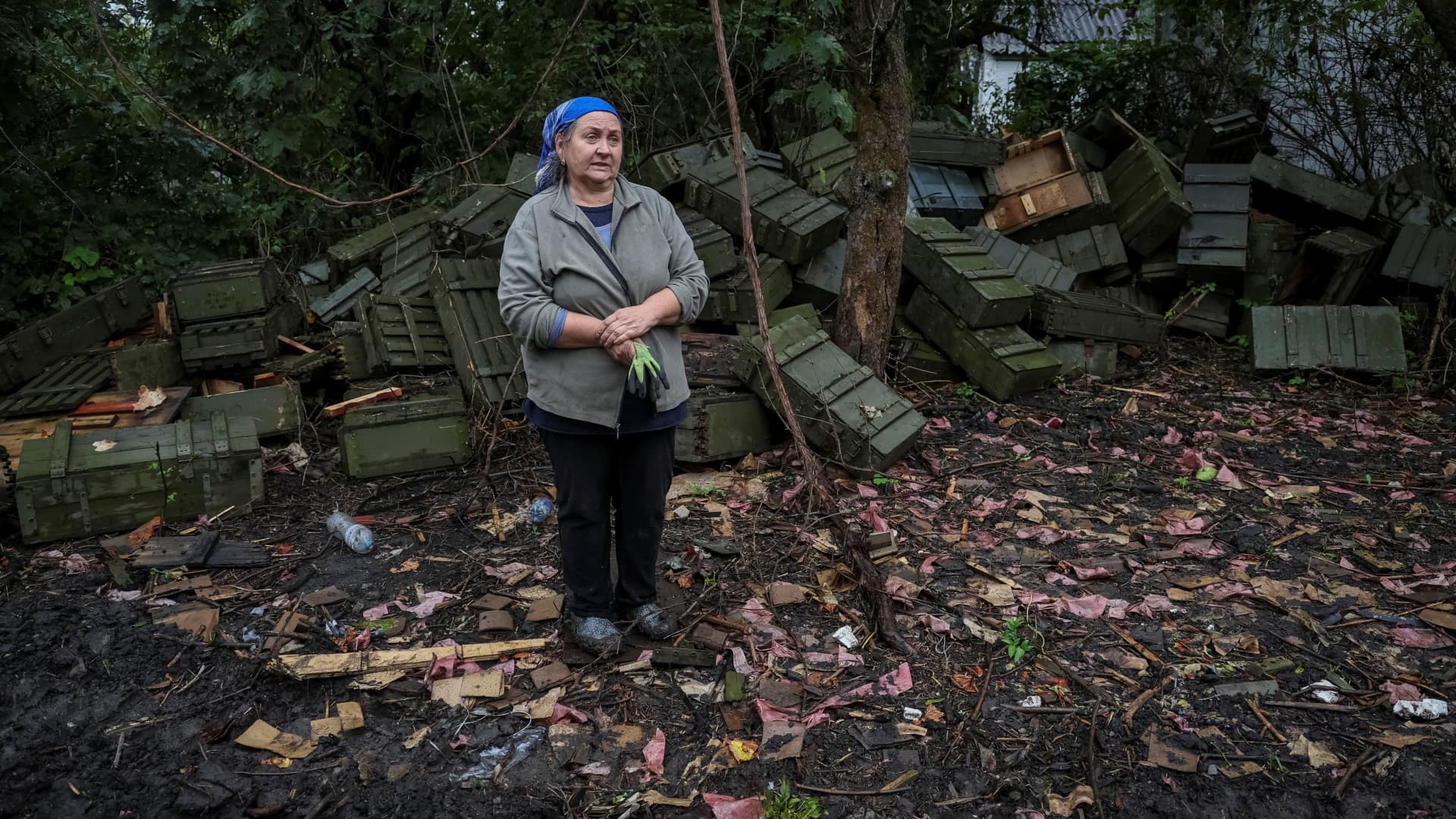 A local resident Olena Kushnir stands in front of ammunition boxes near her destroyed house, amid Russia's attack on Ukraine, in the village of Nova Husarivka, recently liberated by Ukrainian Armed Forces, in Kharkiv region, Ukraine September 15, 2022.