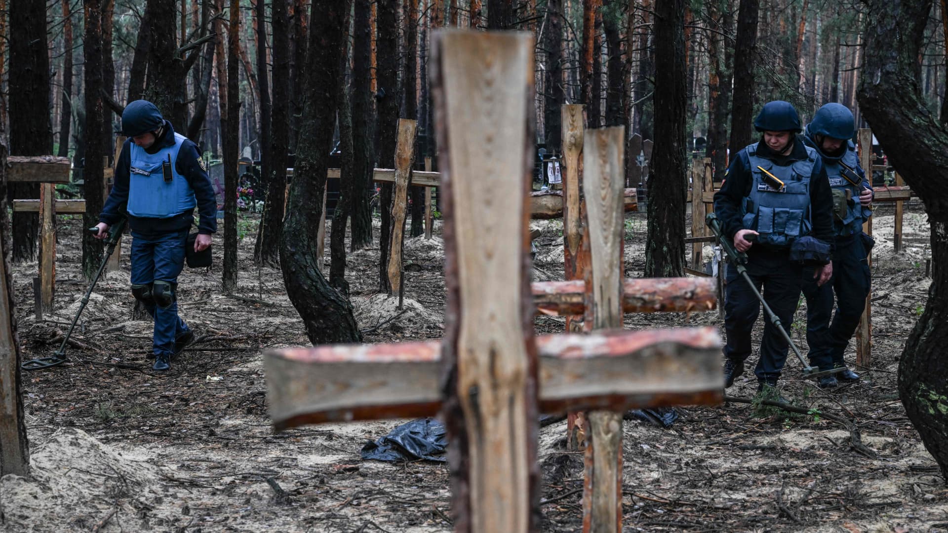 Ukrainian servicemen search for land mines at a burial site in a forest on the outskirts of Izyum, eastern Ukraine on September 16, 2022.