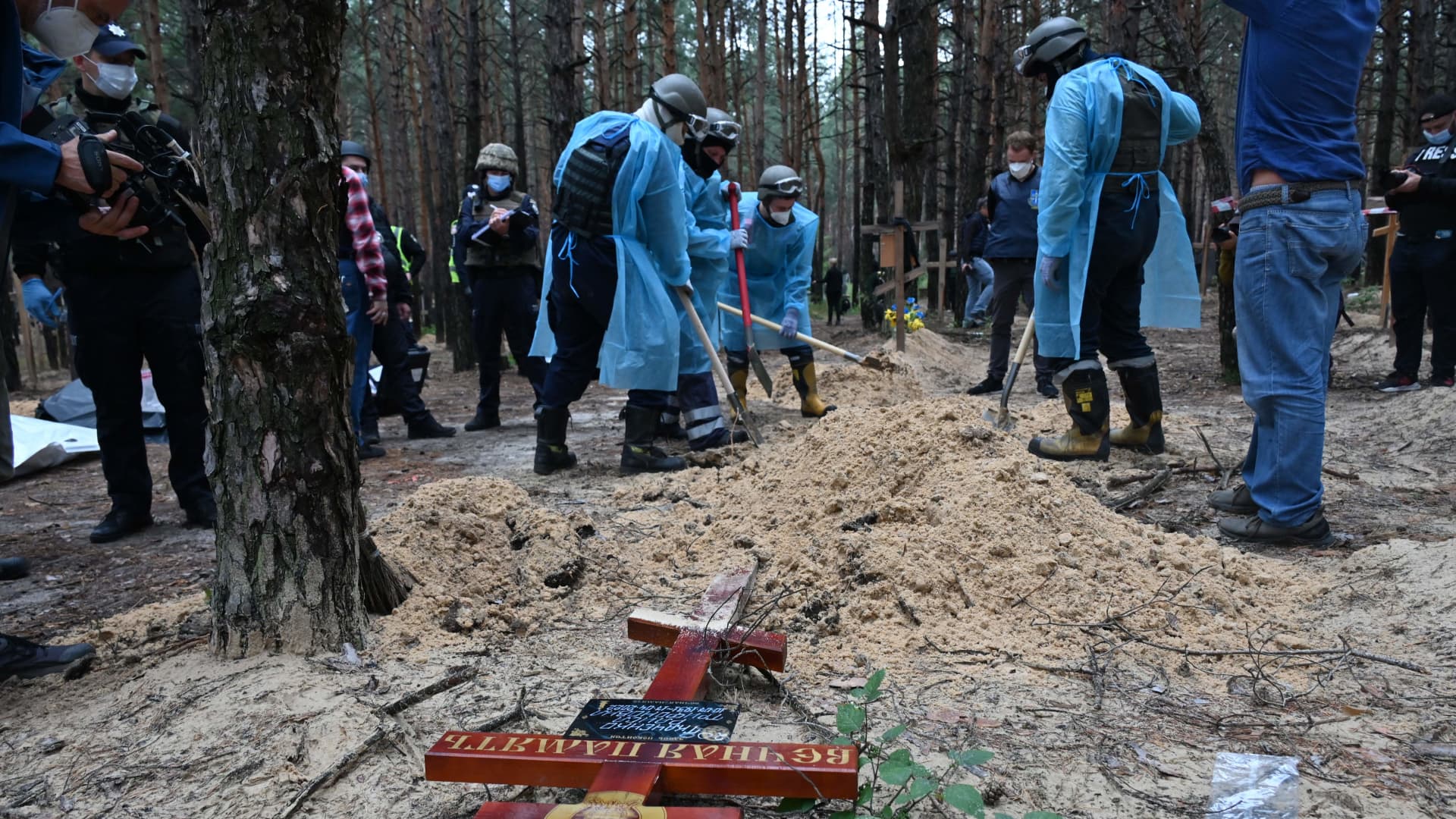 Forensic technicians dig a grave in a forest on the outskirts of Izyum, eastern Ukraine on September 16, 2022. - Ukraine said on September 16, 2022 it had counted 450 graves at just one burial site near Izyum after recapturing the eastern city from the Russians. 