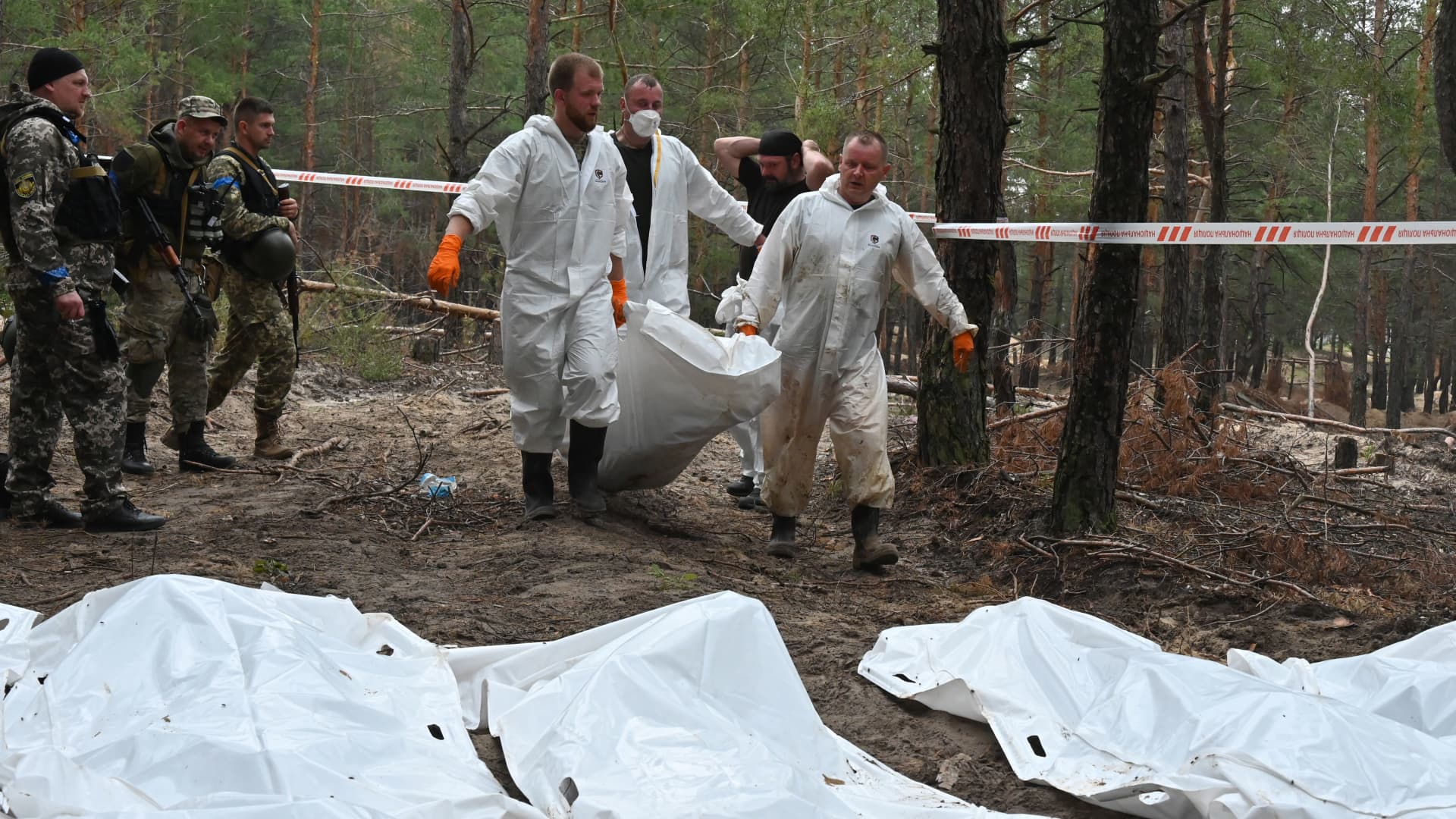 EDITORS NOTE: Graphic content / Forensic technicians carry a body bag in a forest on the outskirts of Izyum, eastern Ukraine on September 16, 2022. 