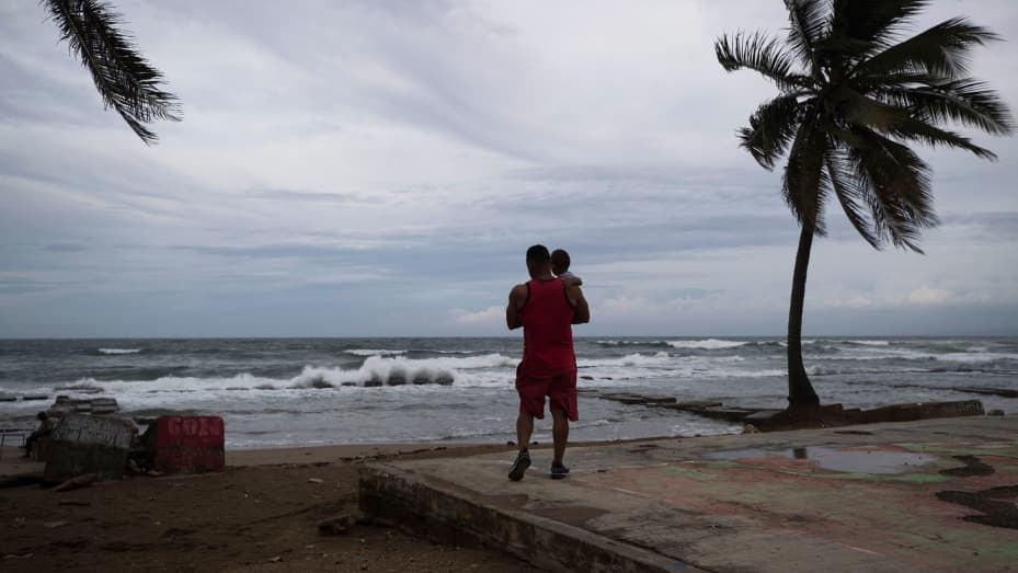 A man stands on the beach with his son in in Nagua, Dominican Republic, on September 18, 2022. Hurricane Fiona made landfall Sunday in Puerto Rico as it passed through the Caribbean.