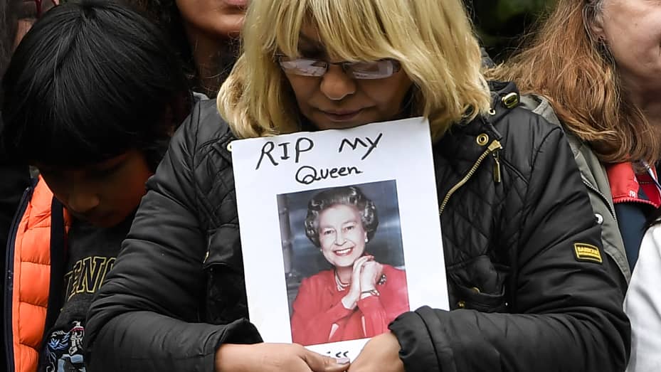TOPSHOT - A well-wisher holds a portrait of Queen Elizabeth II as she waits along the Procession route in London on September 19, 2022, ahead of the State Funeral Service of Britain's Queen Elizabeth II. - Leaders from around the world attended the state funeral of Queen Elizabeth II. The country's longest-serving monarch, who died aged 96 after 70 years on the throne, was honoured with a state funeral on Monday morning at Westminster Abbey. (Photo by LOUISA GOULIAMAKI / AFP) (Photo by LOUISA GOULIAMAKI/AFP