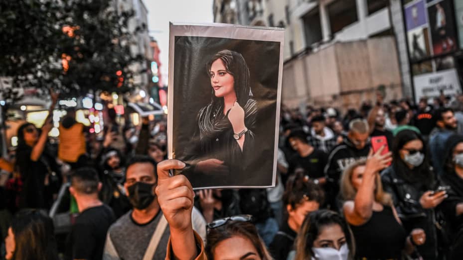 TOPSHOT - A protester holds a portrait of Mahsa Amini  during a demonstration in support of Amini, a young Iranian woman who died after being arrested in Tehran by the Islamic Republic's morality police, on Istiklal avenue in Istanbul on September 20, 2022. - Amini, 22, was on a visit with her family to the Iranian capital when she was detained on September 13 by the police unit responsible for enforcing Iran's strict dress code for women, including the wearing of the headscarf in public. She was declared d