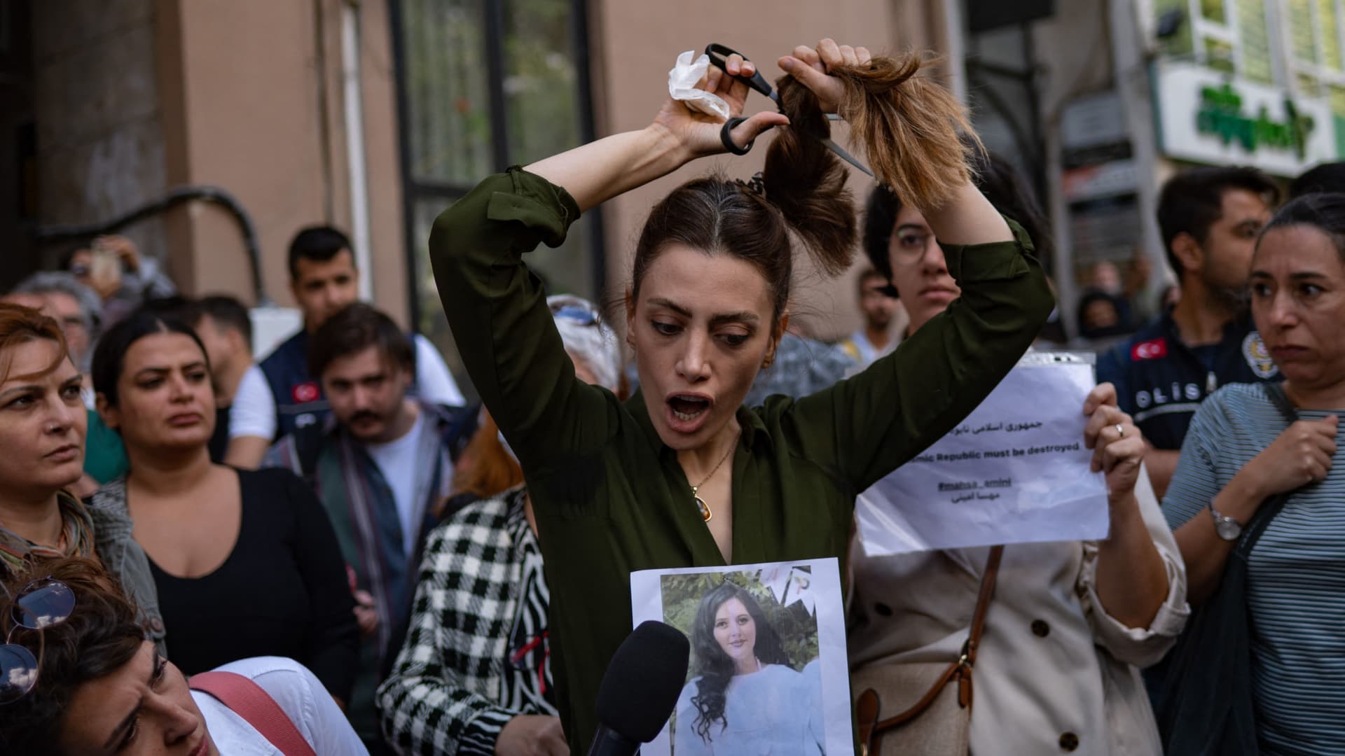 TOPSHOT - Nasibe Samsaei, an Iranian woman living in Turkey, cuts her ponytail off during a protest outside the Iranian consulate in Istanbul on September 21, 2022, following the death of an Iranian woman after her arrest by the country's morality police in Tehran.