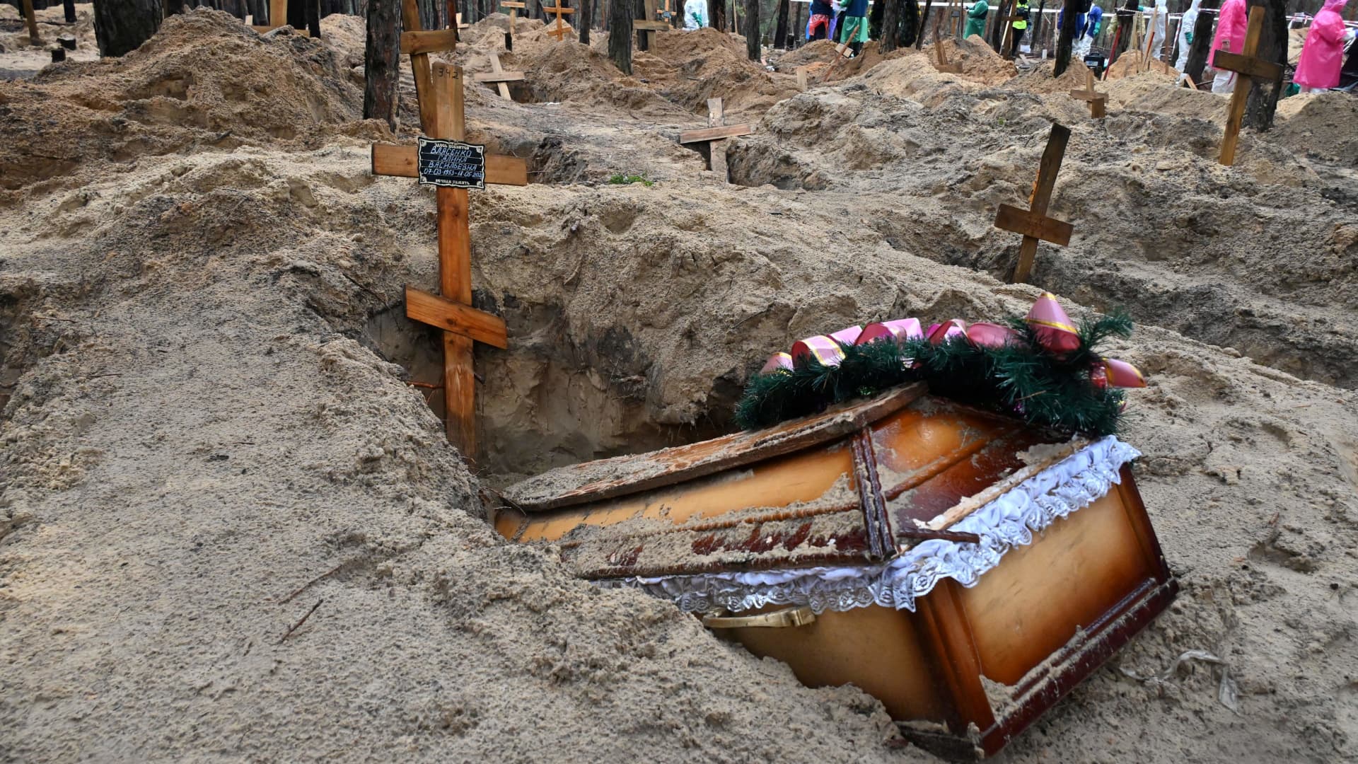 A coffin sticks out of a grave in a forest near Izium, eastern Ukraine, on Sept. 23, 2022, where Ukrainian investigators uncovered more than 440 graves after the city was recaptured from Russian forces, bringing fresh claims of war atrocities.