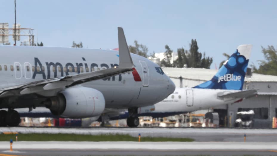 An American Airlines plane takes off near a parked JetBlue plane at the Fort Lauderdale-Hollywood International Airport on July 16, 2020 in Fort Lauderdale, Florida.