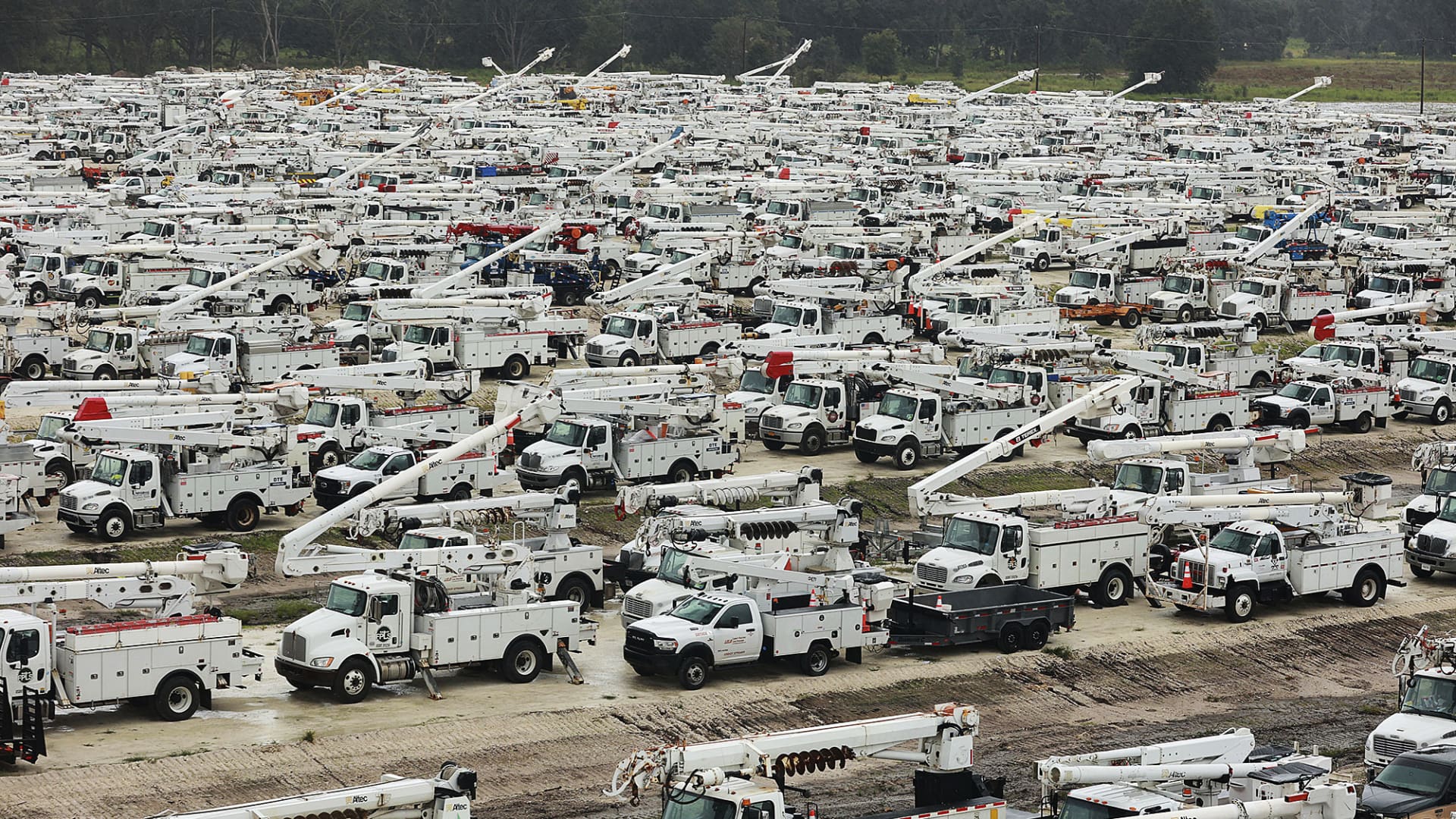 Utility trucks are staged in a rural lot in The Villages of Sumter County, Fla., Wednesday morning, Sept. 28, 2022, in preparation for Hurricane Ian.