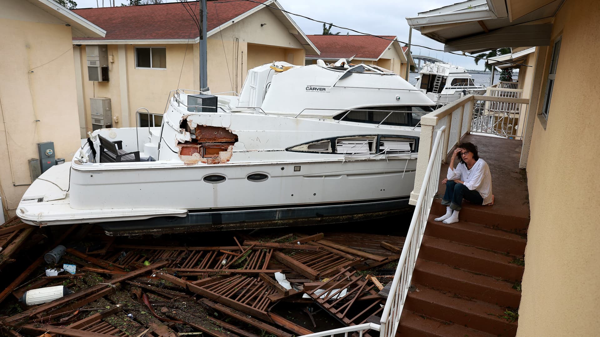 Brenda Brennan sits next to a boat that pushed against her apartment when Hurricane Ian passed through the area on September 29, 2022 in Fort Myers, Florida.