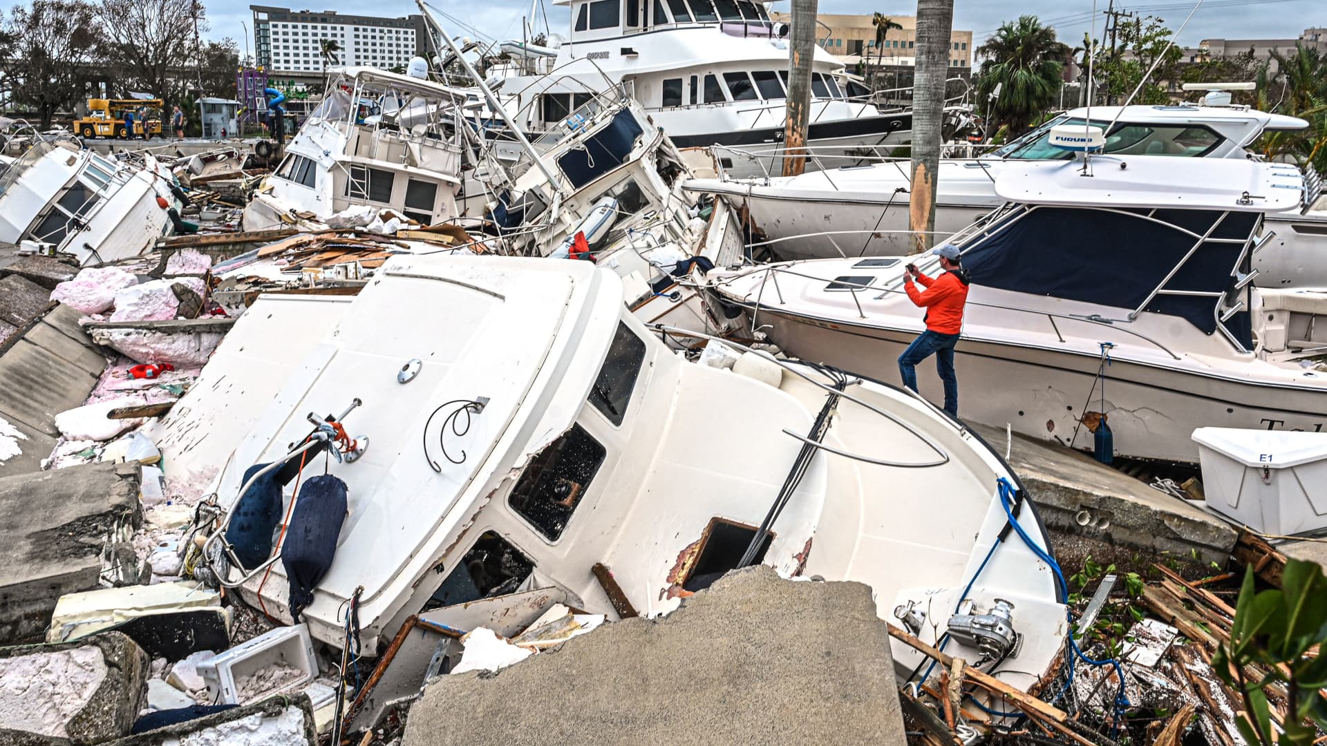 A man takes photos of boats damaged by Hurricane Ian in Fort Myers, Florida, on September 29, 2022.