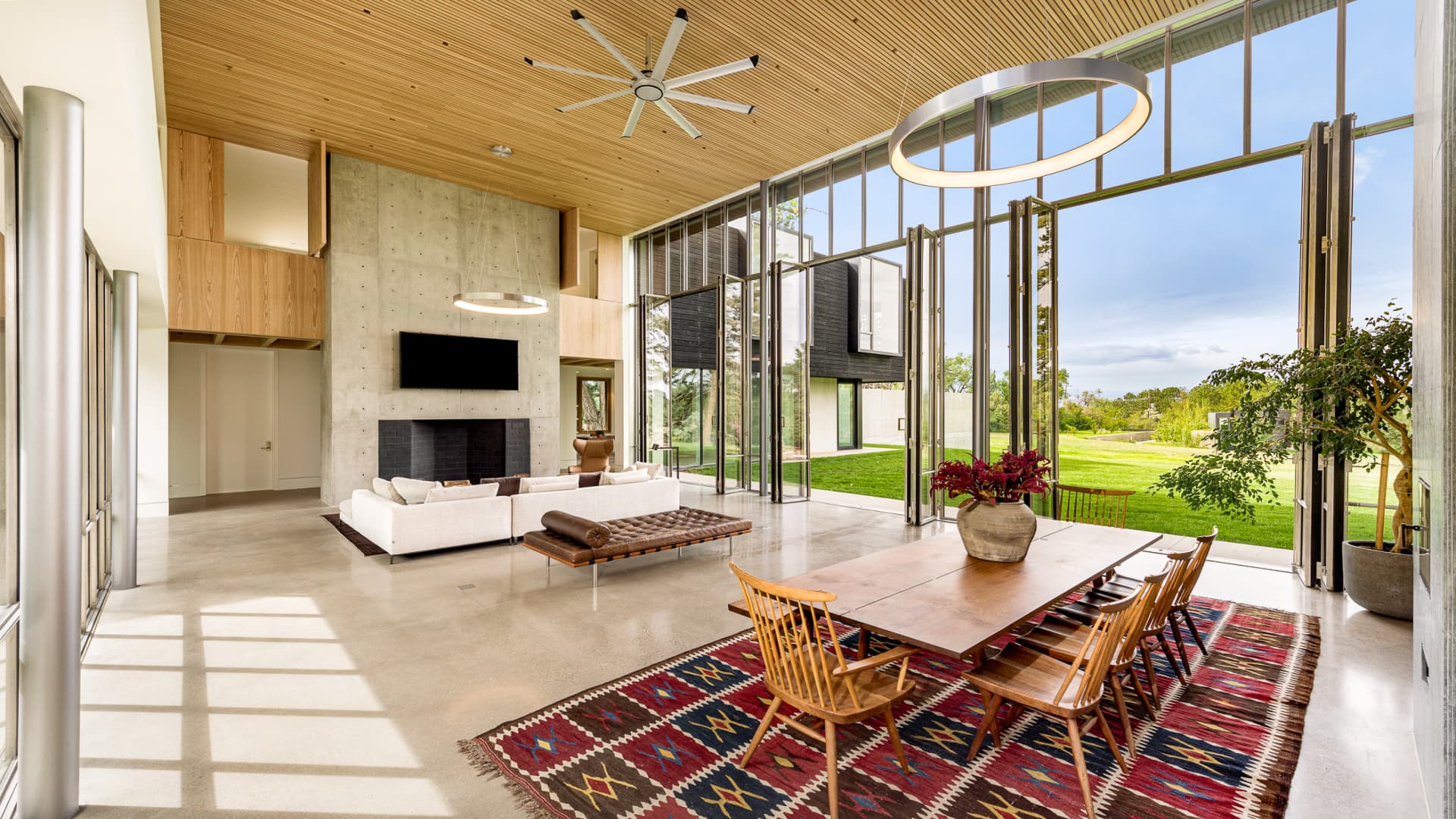 The main home's great room includes 22 ft tall ceilings, polished concrete floors and a wall of floor-to-ceiling glass that opens to a view of the Rocky Mountains.