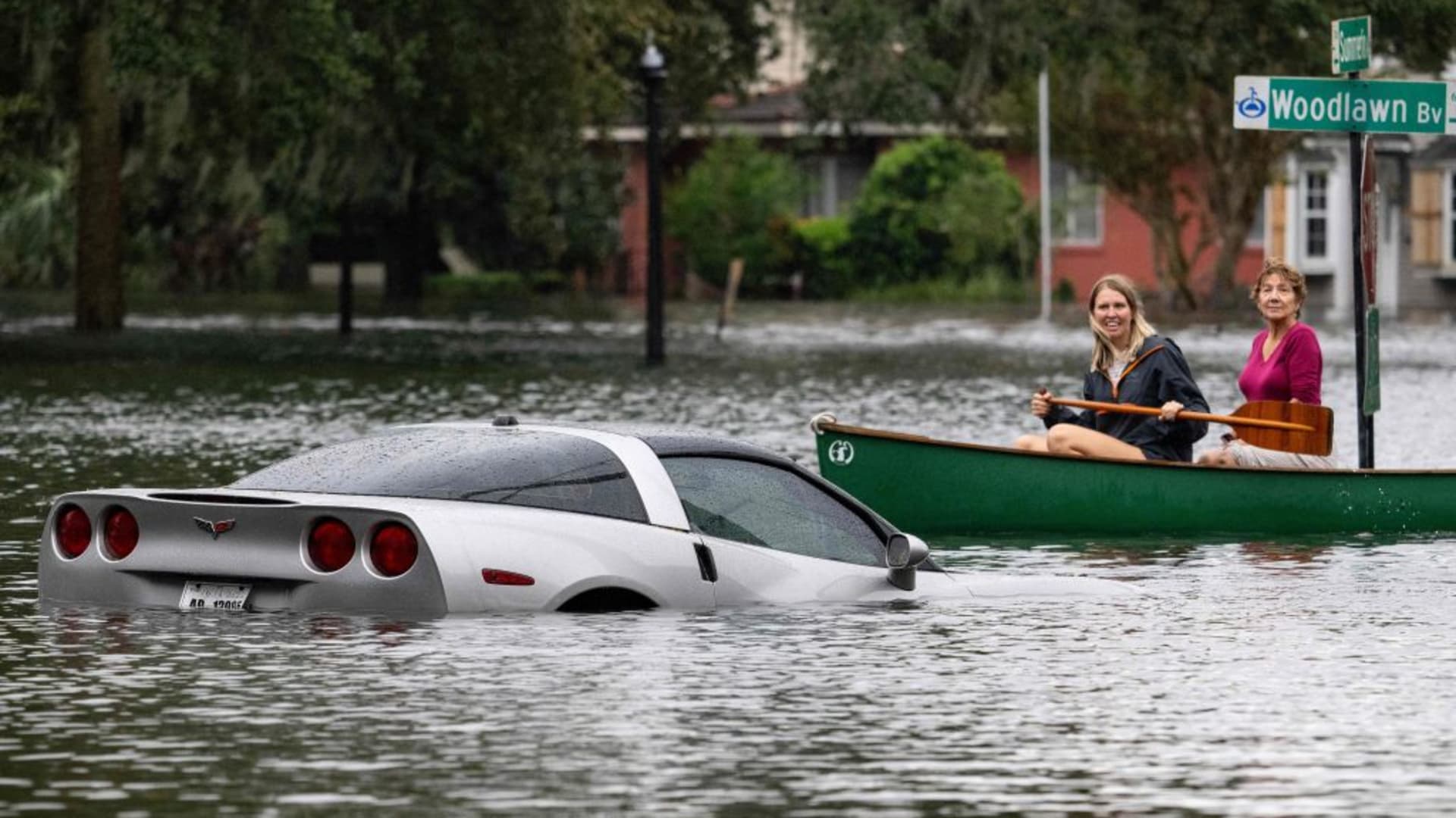 People paddle by in a canoe next to a submerged Chevy Corvette in the aftermath of Hurricane Ian in Orlando, Florida on September 29, 2022.