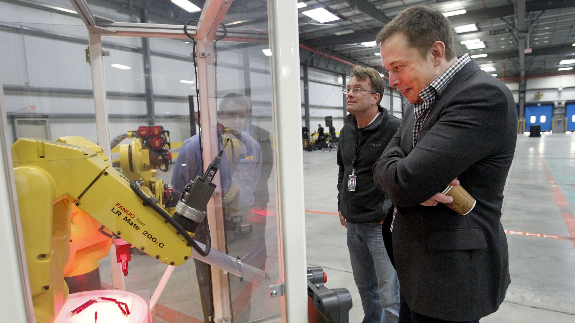 Elon Musk looks at a robot display during a tour of the new Tesla Motors auto plant, formerly operated New United Motor Manufacturing Inc. (NUMMI), in Fremont, California, U.S., on Wednesday, Oct. 27, 2010.