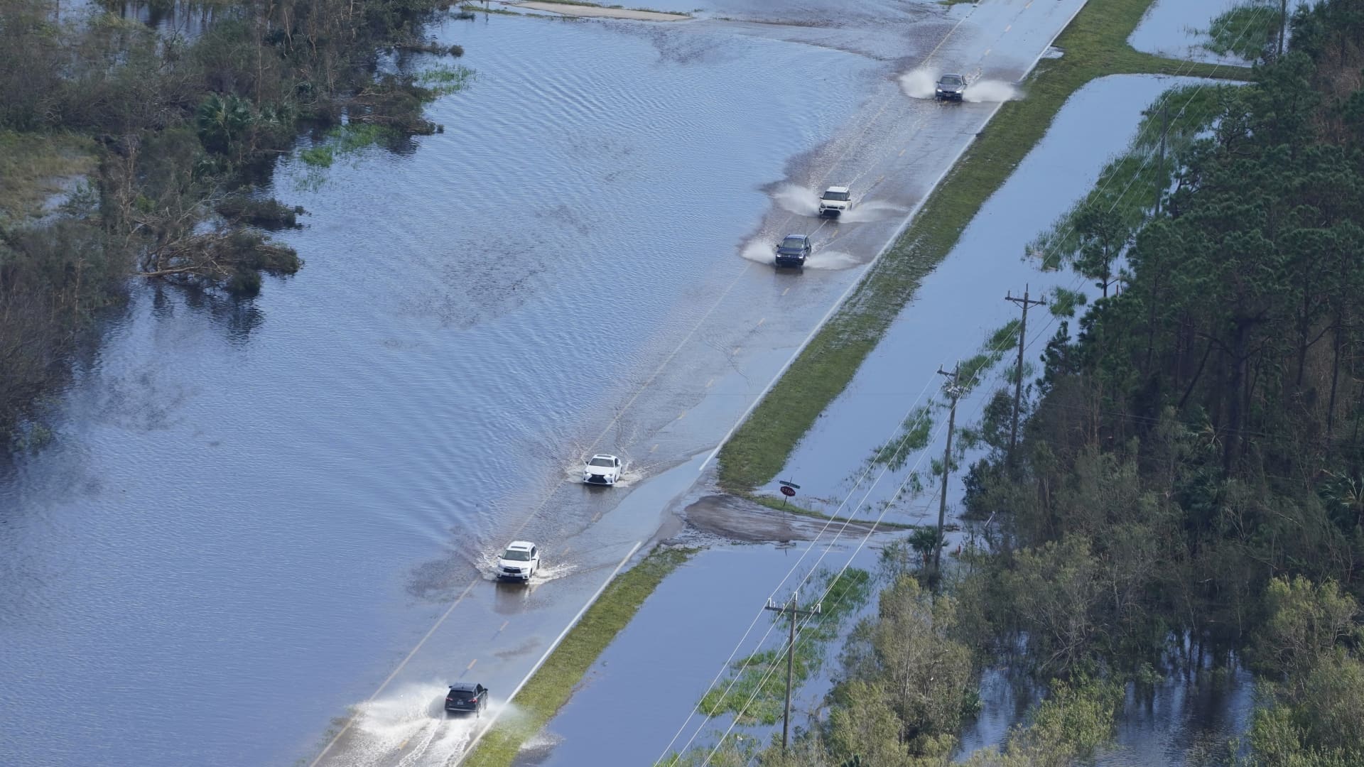 Cars drive on a flooded street caused by Hurricane Ian Thursday, Sept. 29, 2022, in Fort Myers, Fla.