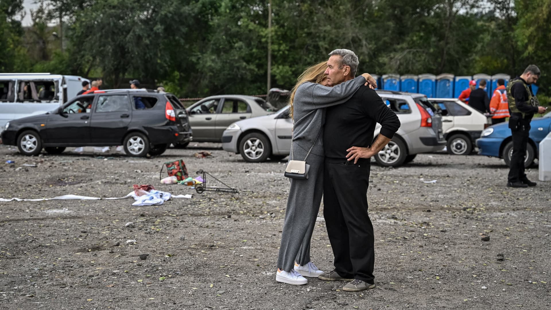 A couple hug each other near cars damaged by a missile strike on a road near Zaporizhzhia on September 30, 2022, amid the Russian invasion of Ukraine.