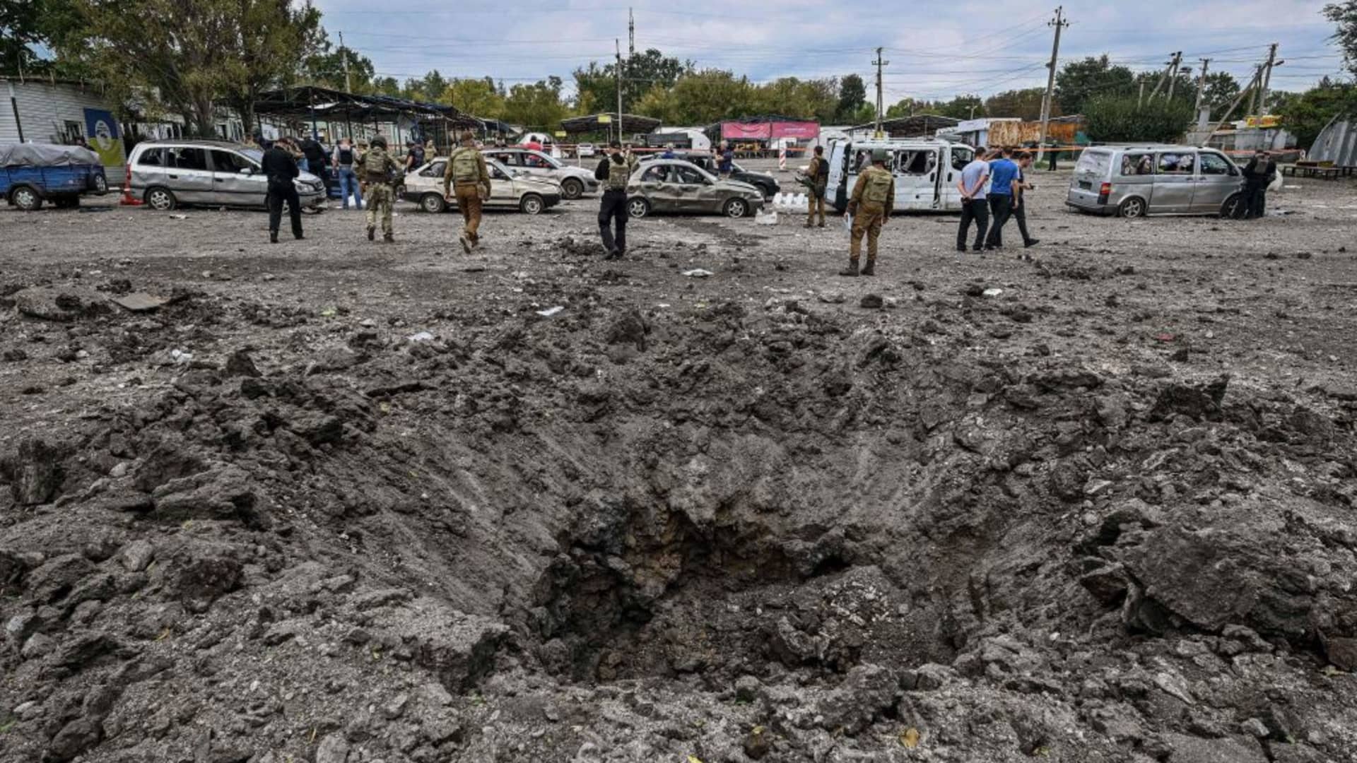 Ukrainian servicemen walk by a crater left by a missile strike near Zaporizhzhia on September 30, 2022, amid the Russian invasion of Ukraine.
