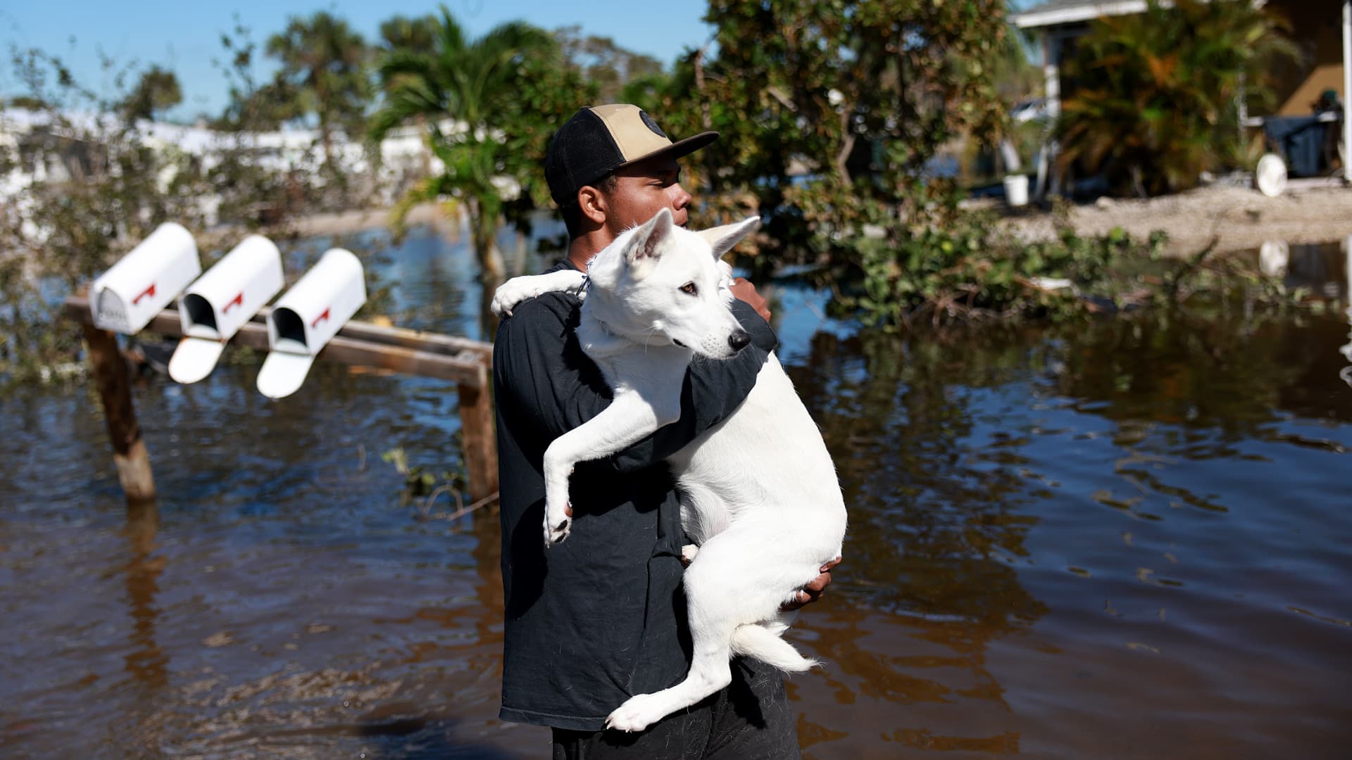 Jordan Reidy carries his dog, Ivory, back to their second-floor apartment after fleeing when Hurricane Ian passed through the area on September 30, 2022 in Fort Myers, Florida.
