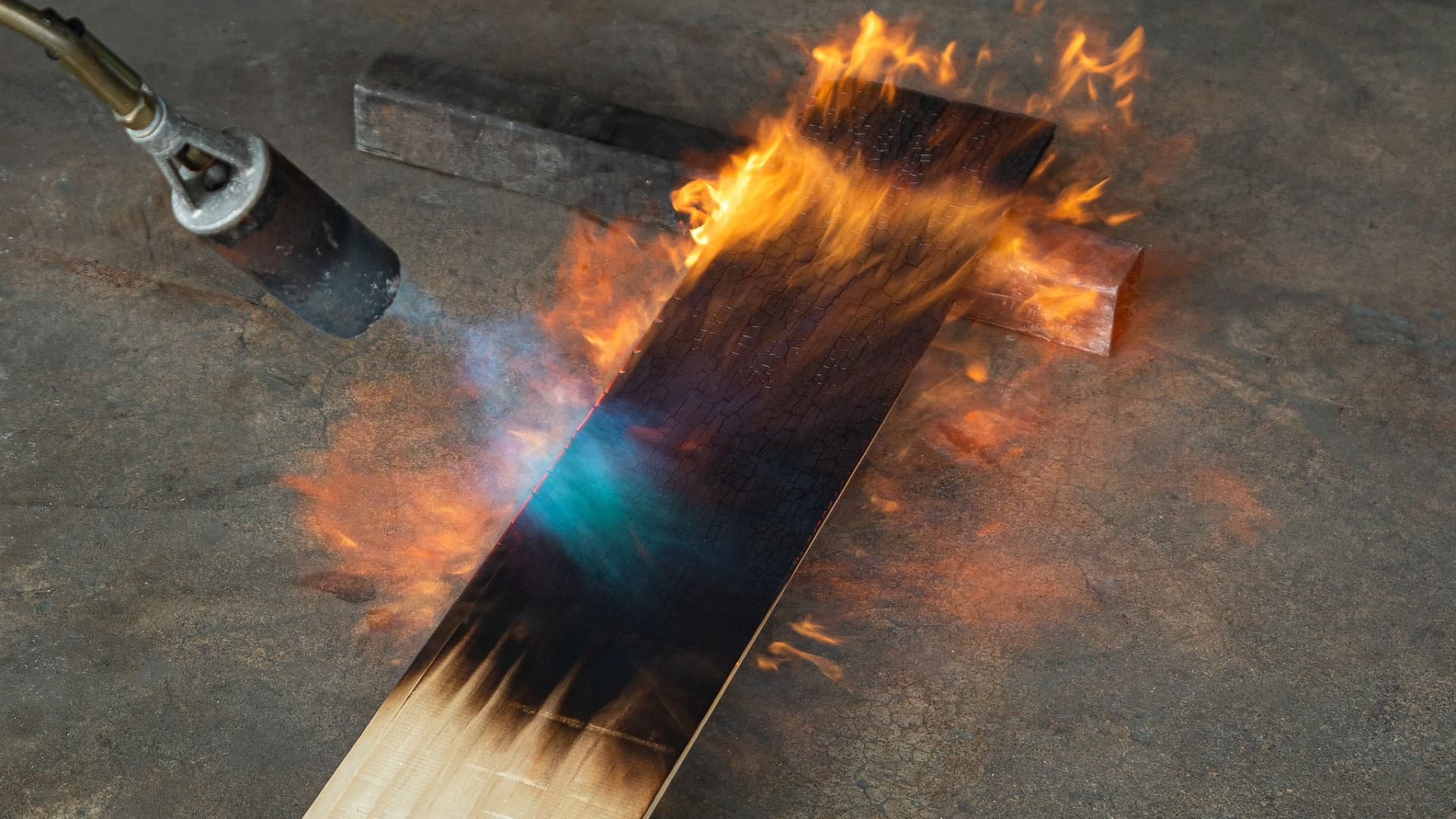 A piece of wood at Delta Millworks is burned with a torch to give it a distinctive charred finish.