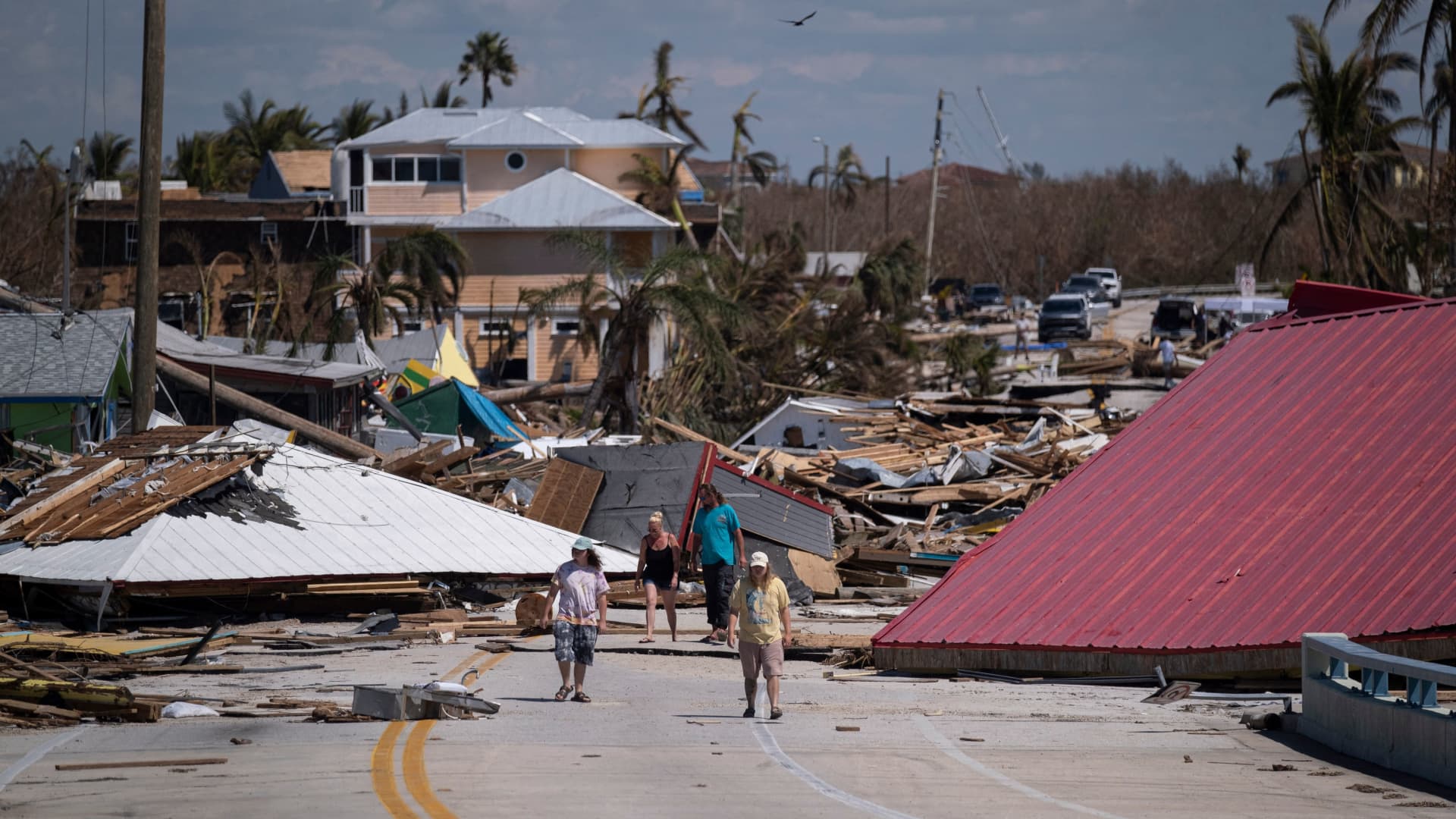 People walk pass destroyed houses and businesses in the aftermath of Hurricane Ian in Matlacha, Florida on October 1, 2022. 