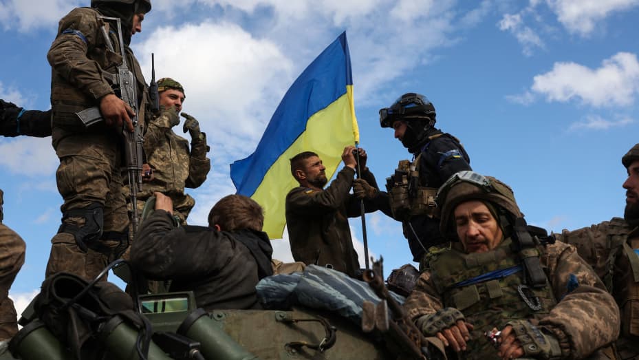 Ukrainian soldiers adjust a national flag atop a personnel armoured carrier on a road near Lyman, Donetsk region on October 4, 2022, amid the Russian invasion of Ukraine.