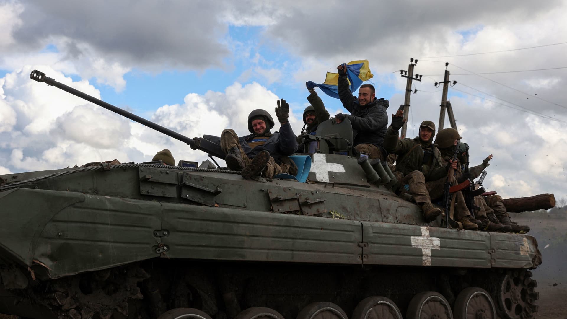 Ukrainian soldiers wave a national flag as they ride on a personnel armoured carrier on a road near Lyman, Donetsk region on October 4, 2022, amid the Russian invasion of Ukraine.