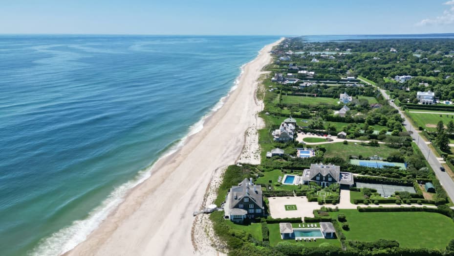 The pair of beachfront homes with two pools and a tennis court in the foreground of the photo are the La Dune estate.