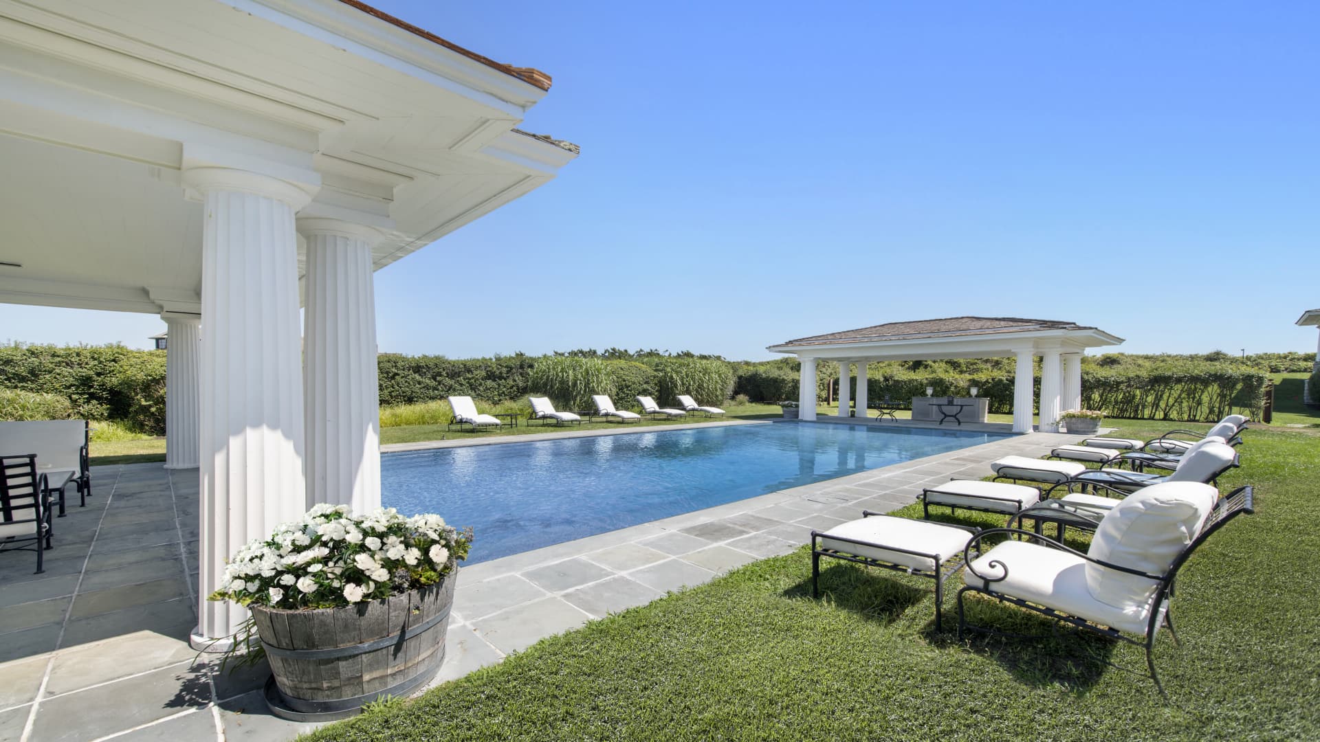 The main home's swimming pool is flanked by two bars and white columns.